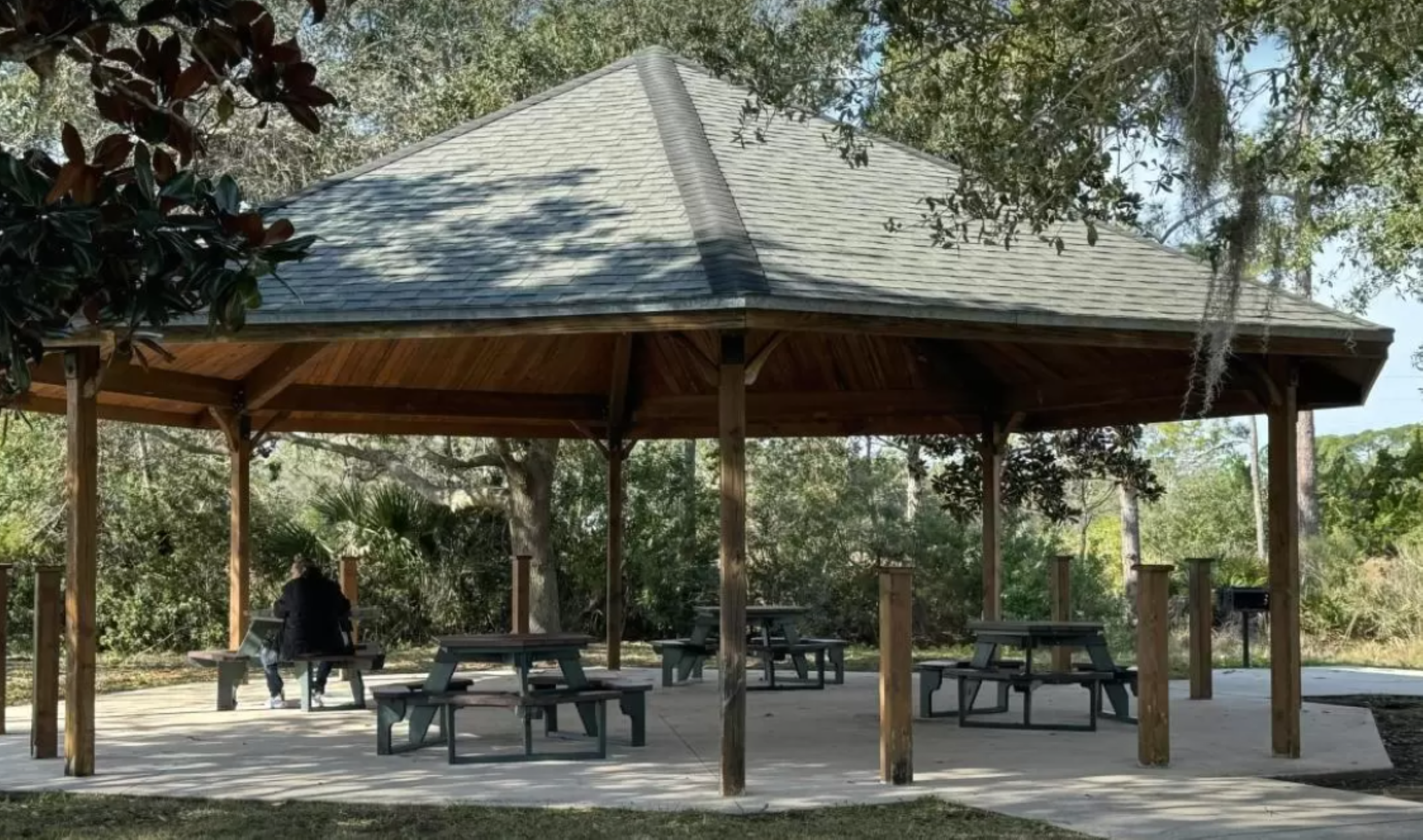 A man relaxes in a chair at Pomar Park, enjoying the warmth of a sunny day. 