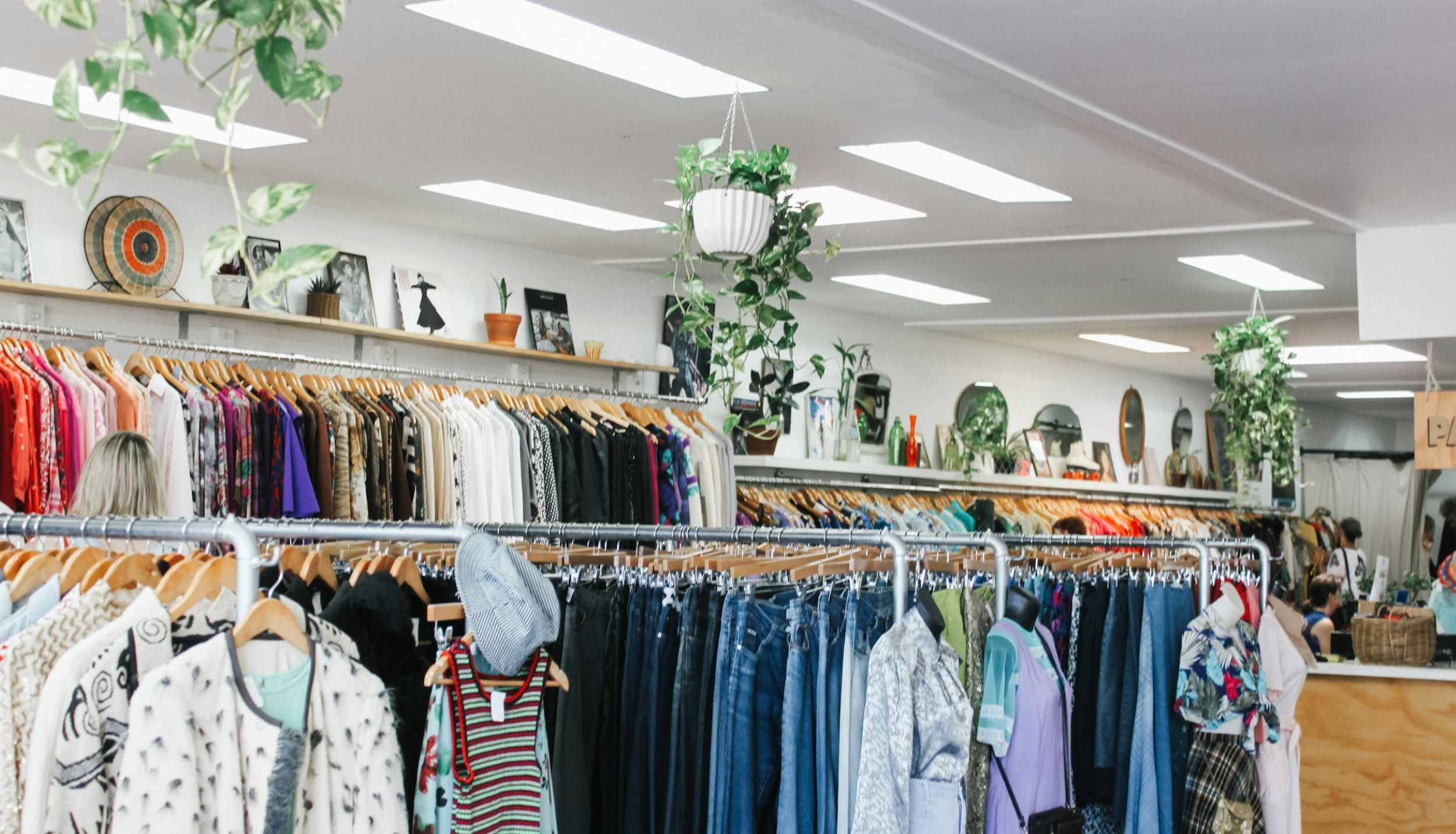 Several racks of clothing are on display at a thrift store.