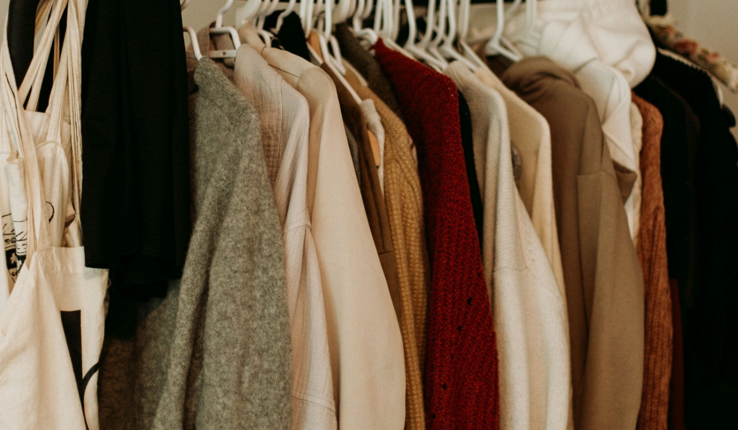 A rack containing sweaters is on display at a thrift store.