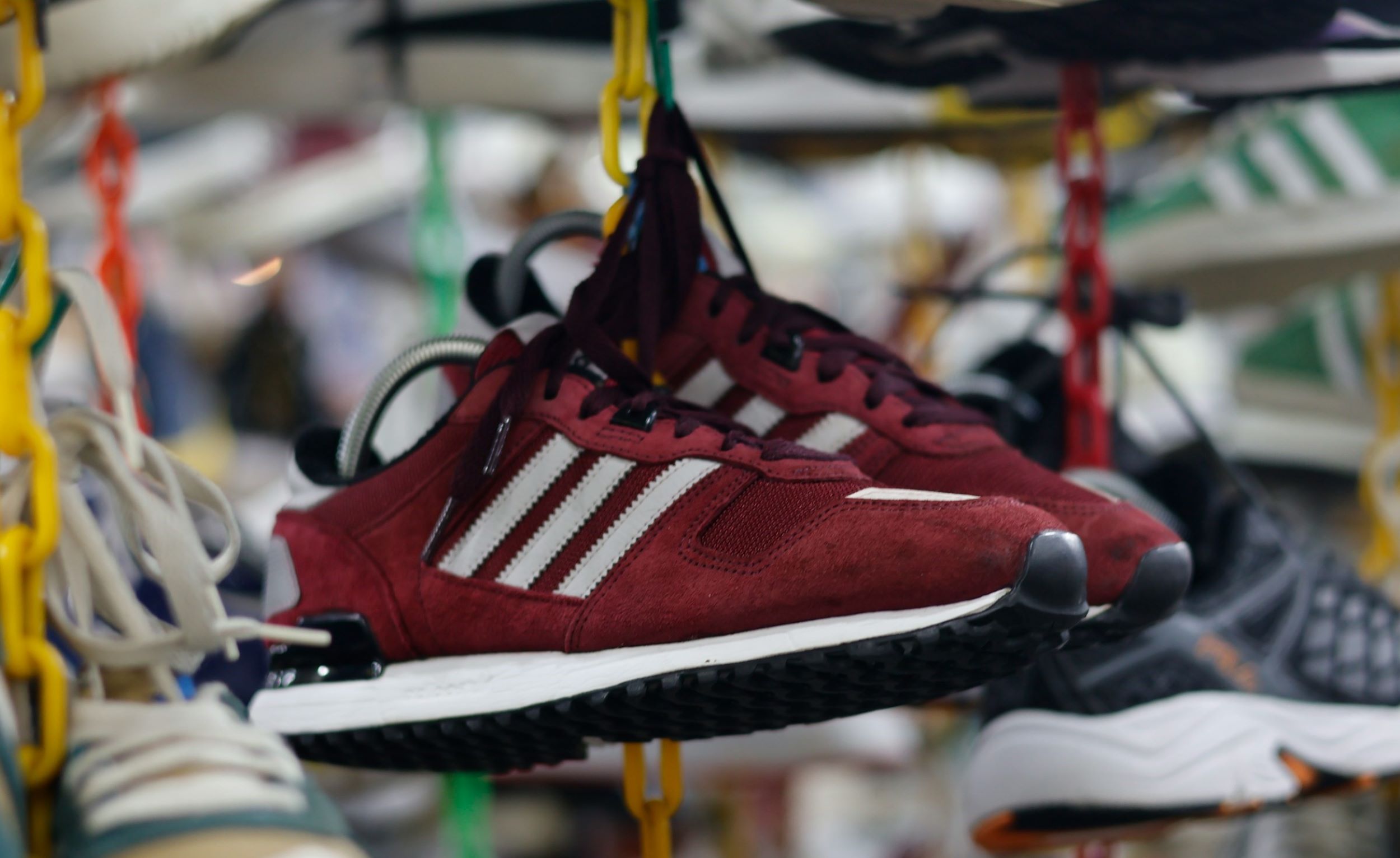 A pair of shoes dangle by their laces inside a store.
