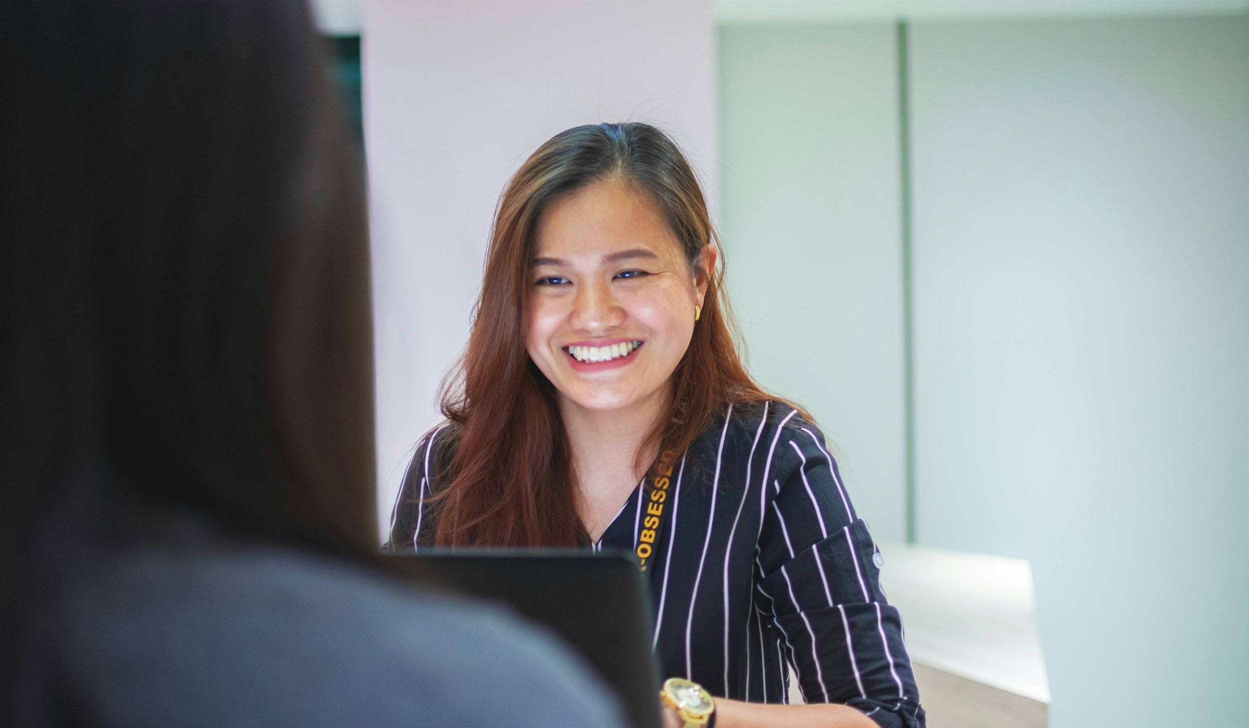 A woman smiles while typing on her computer.