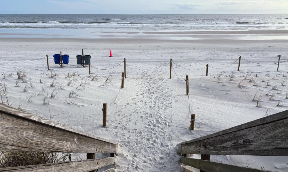 The image captures a scenic view of the sandy shoreline and the beach stretching into the distance.