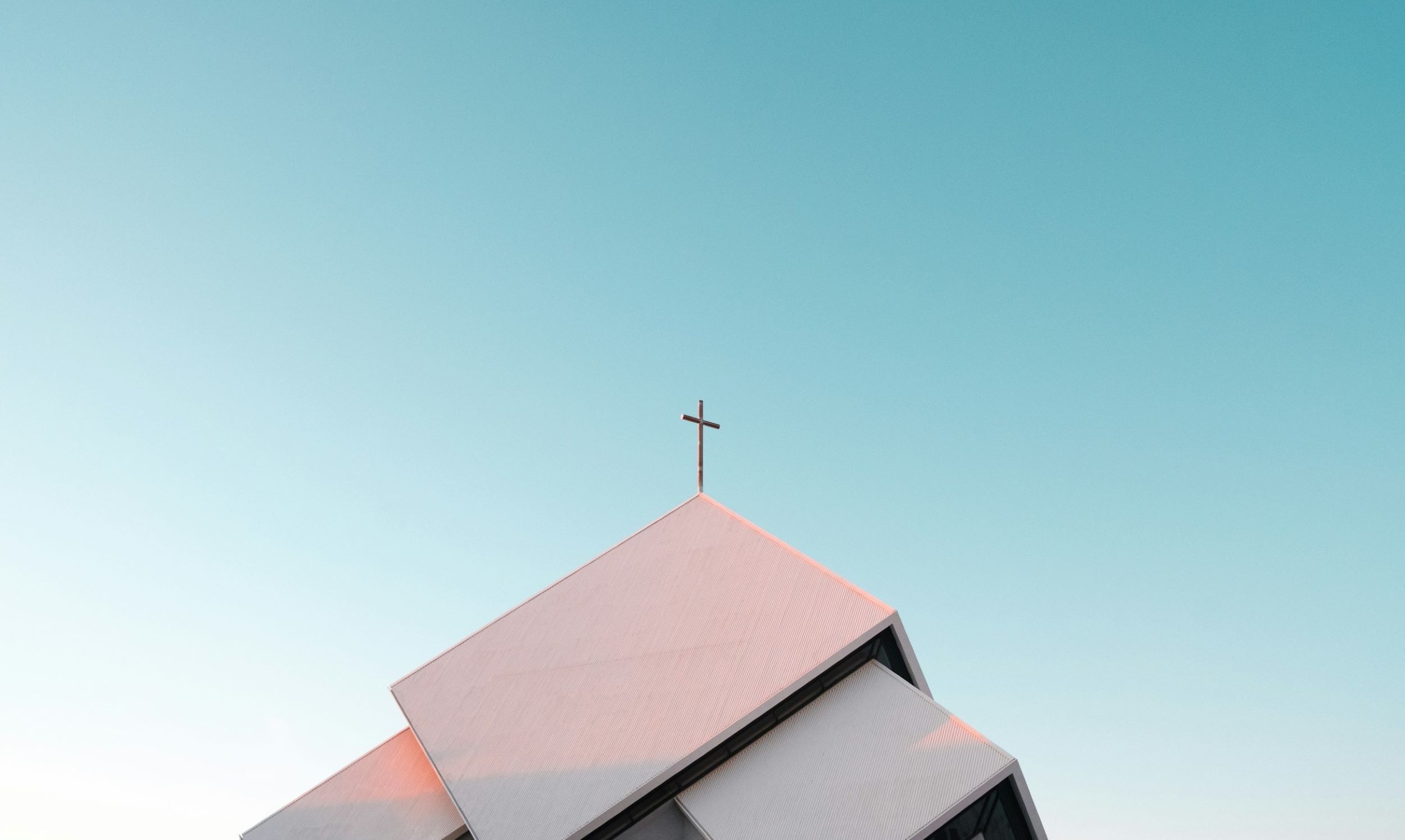 A cross stands atop the roof of a church.