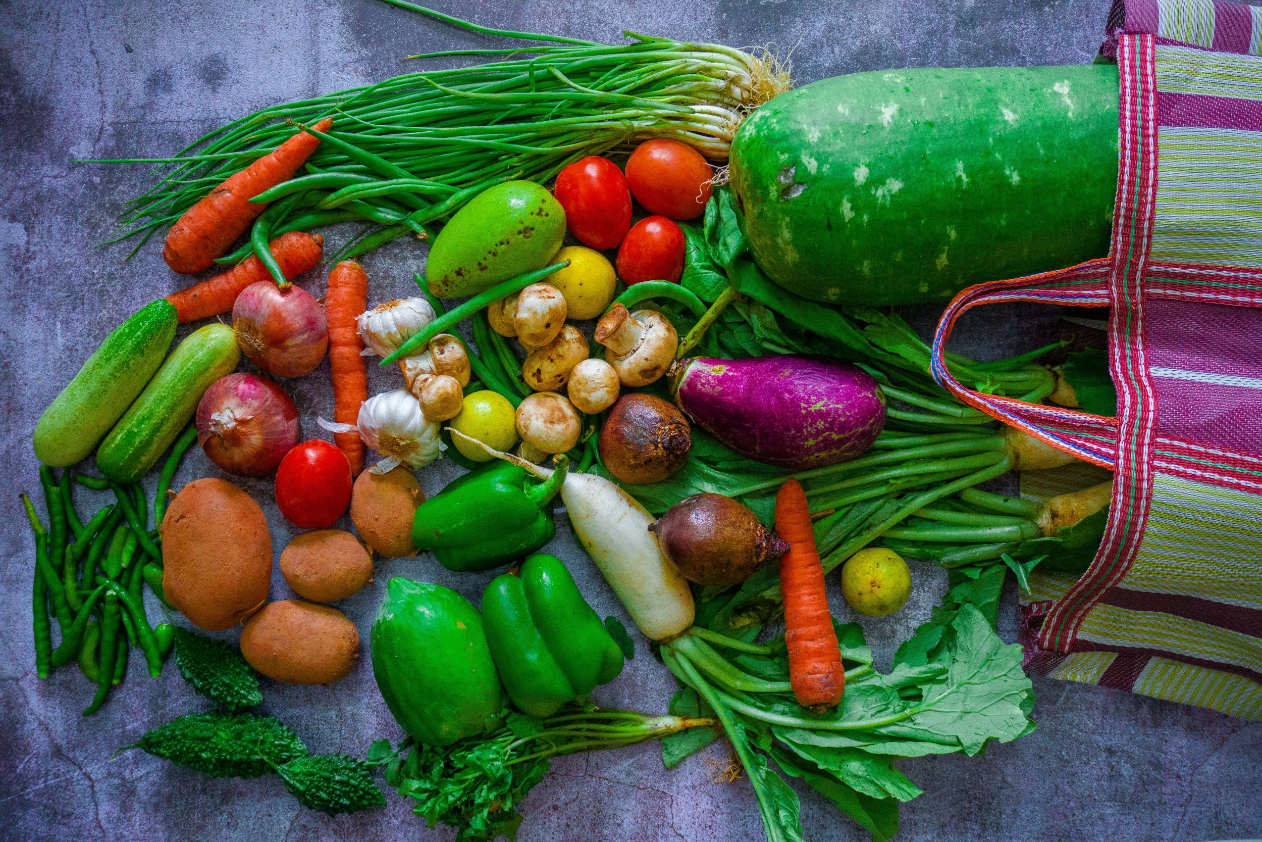 Fresh vegetables are arranged against a blue backdrop.