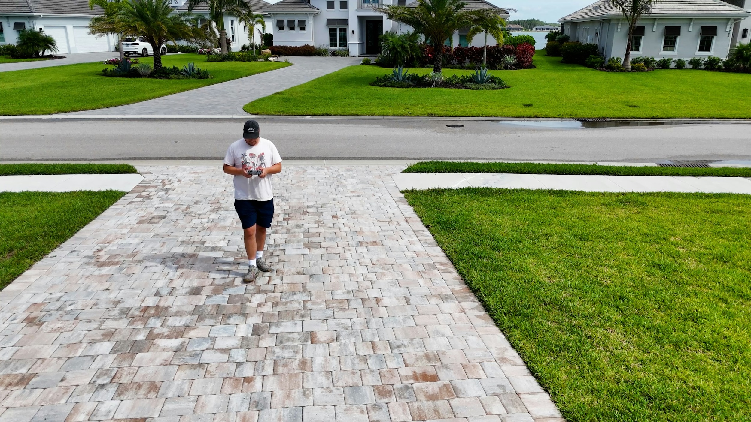 A man stares at his cellphone while walking toward a house.