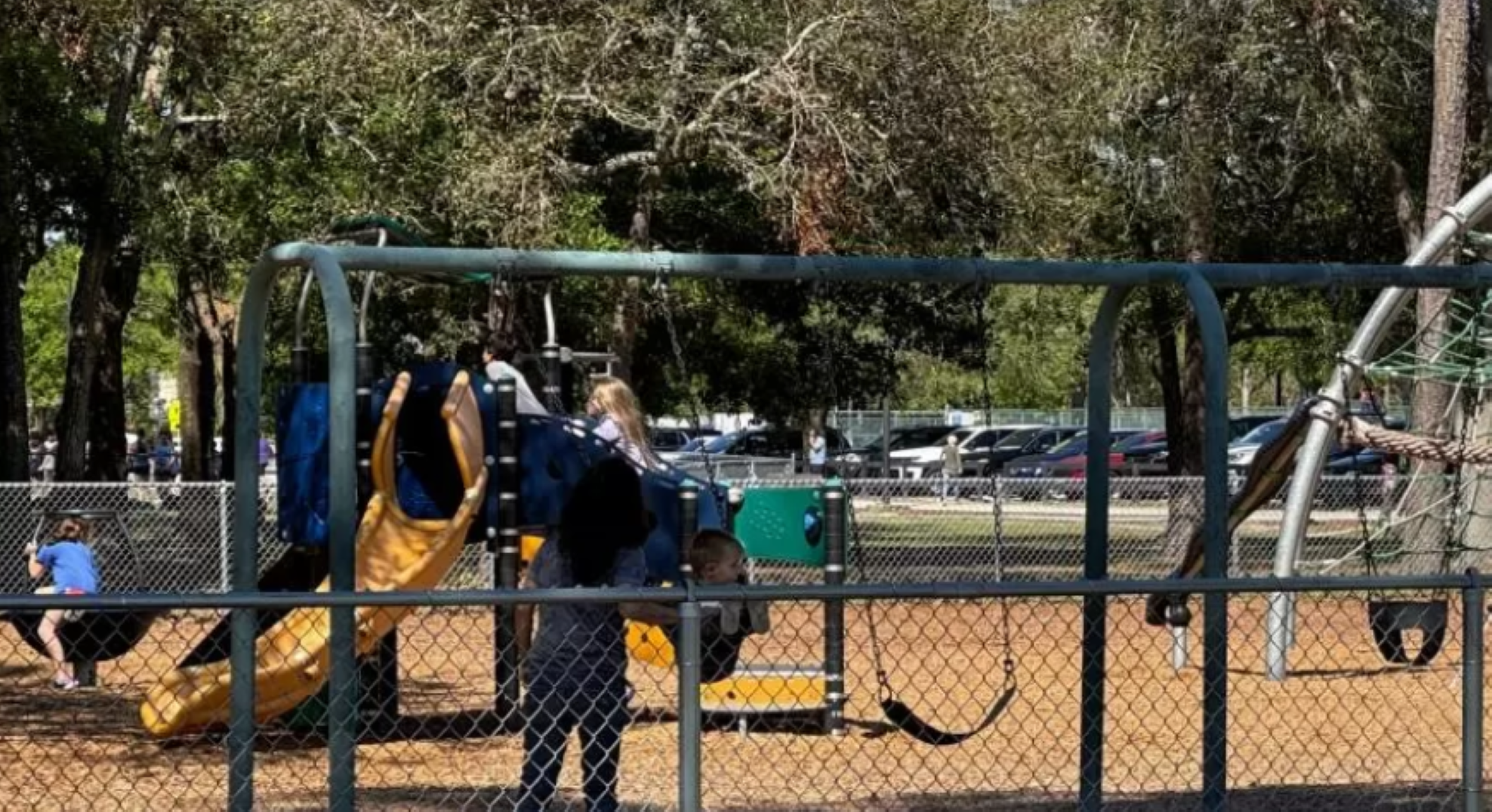 A man gently pushes a swing under the warm sun.