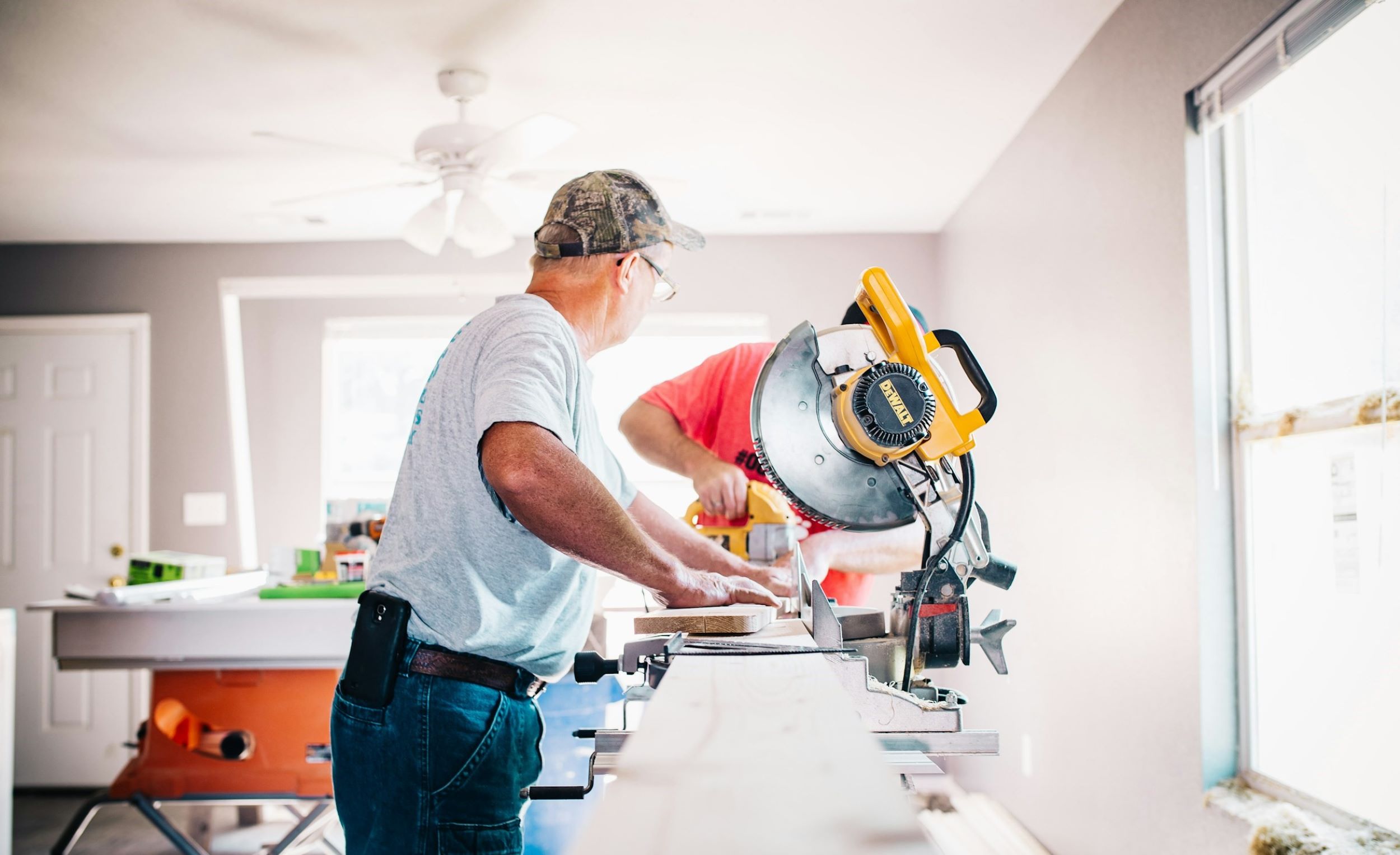 Two men use tools to remodel a kitchen.