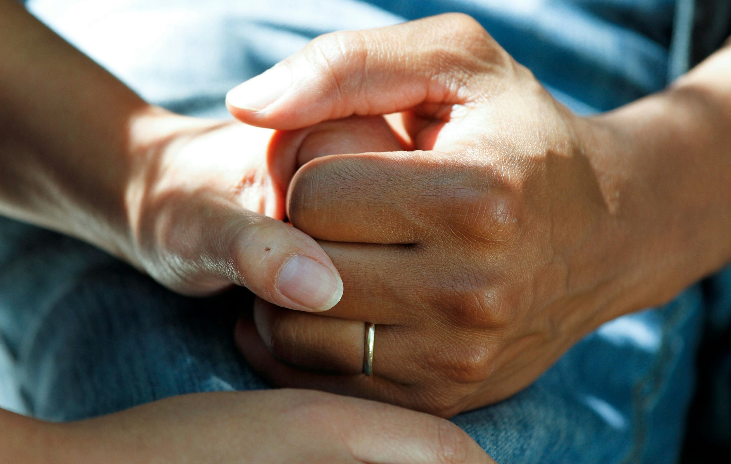 A woman holds a patient's hand.