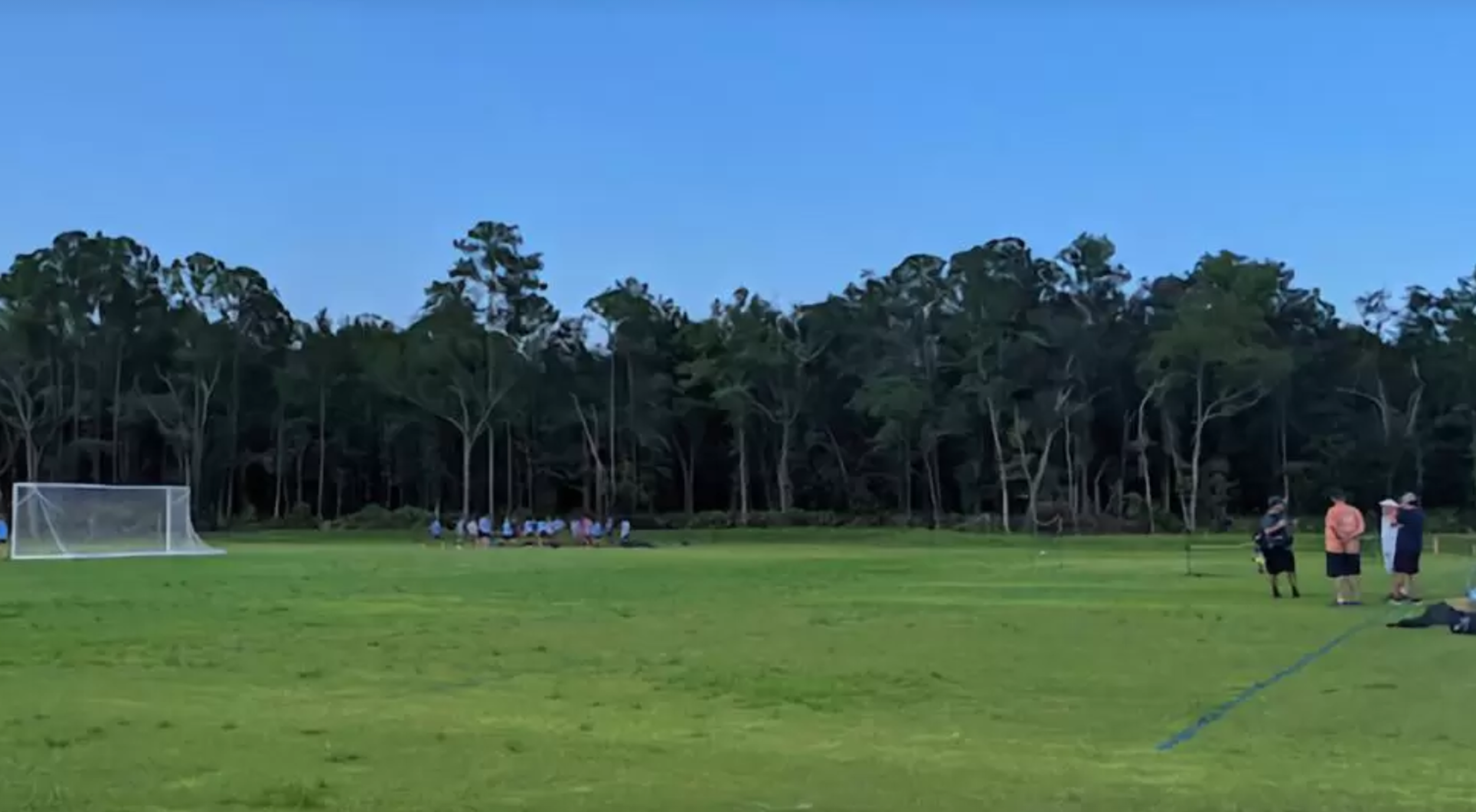 A group of men stands on the grass just a few feet from a soccer goal.