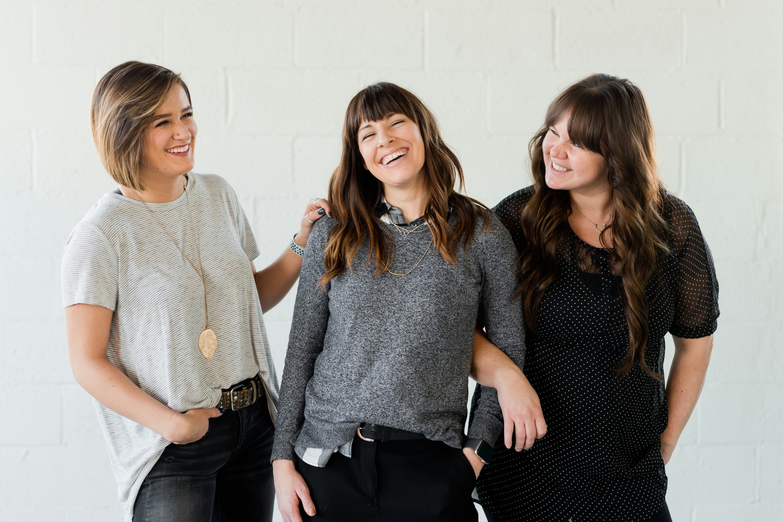 Three women smile in front of a white backdrop.