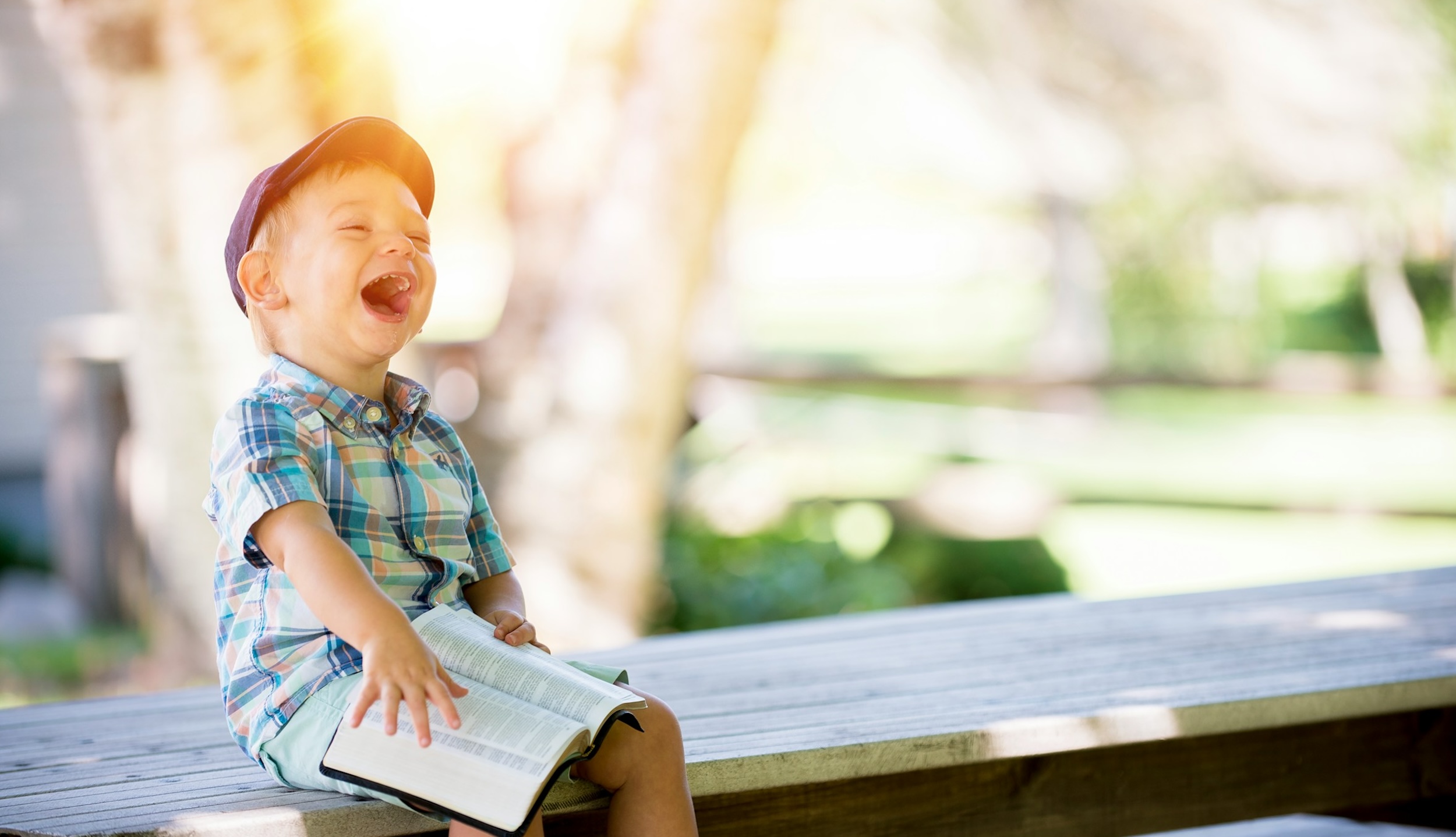 A child laughs while sitting on a bench.