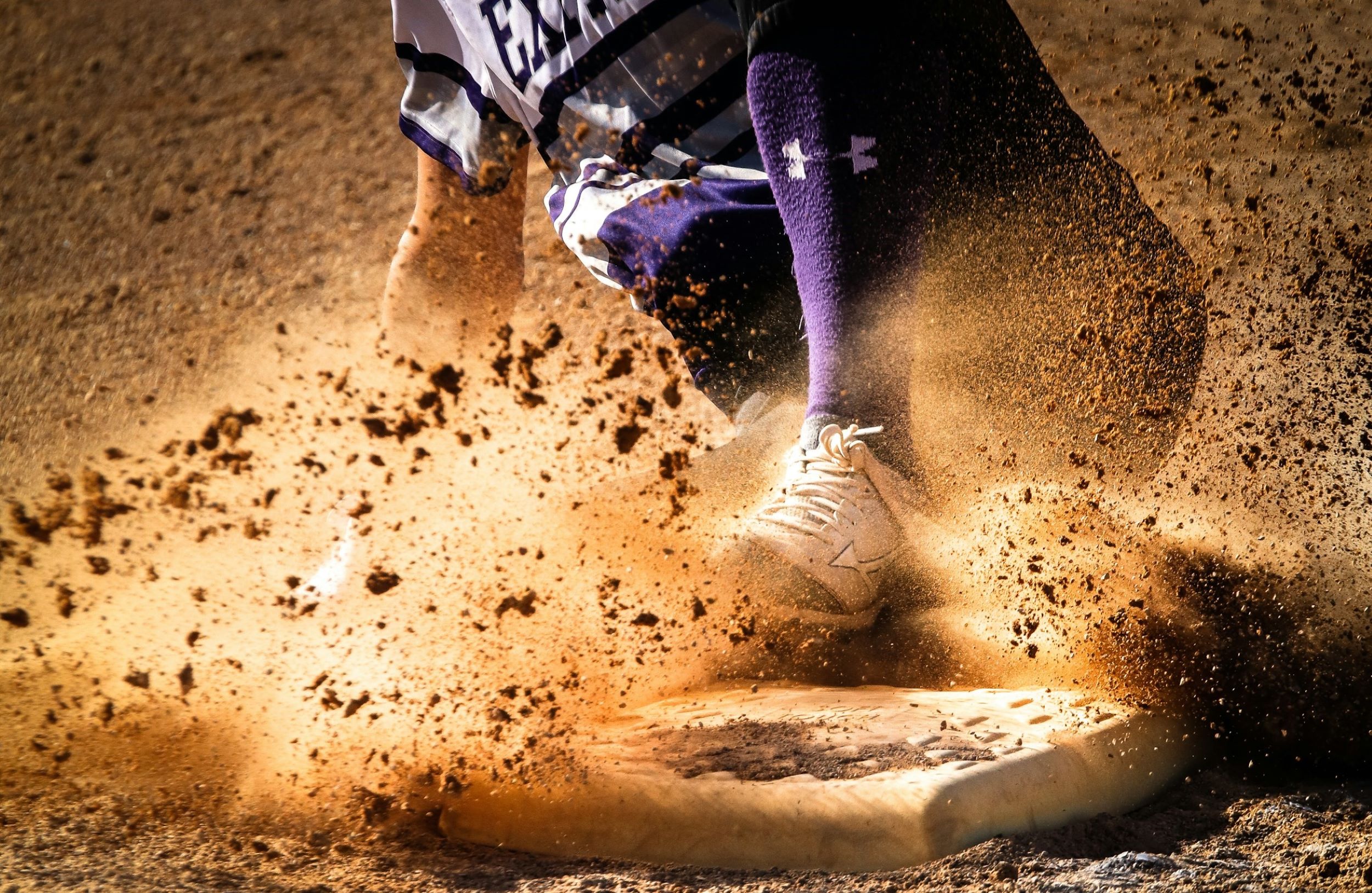 A baseball player runs and slides on base.