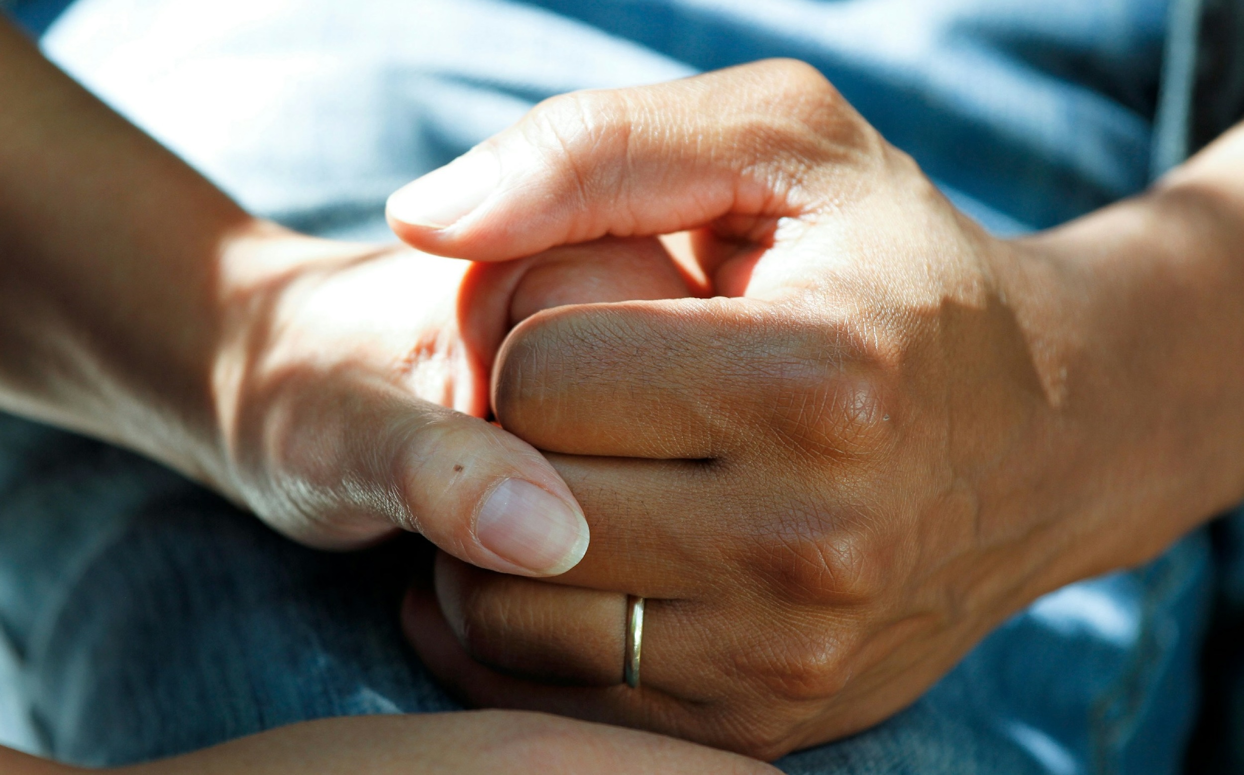A cancer patient holds hands with a loved one. 