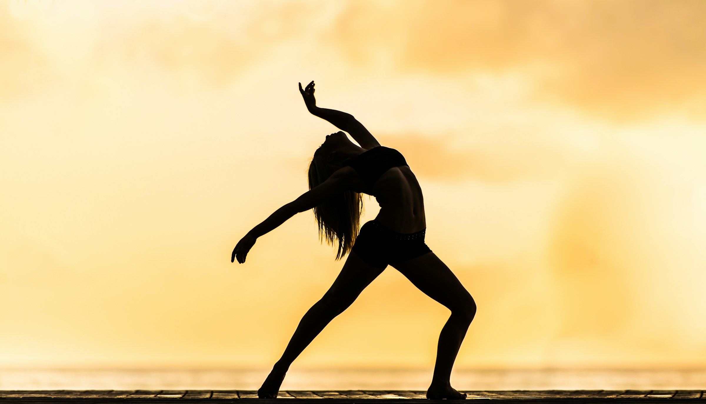 A woman dances in front of a yellow backdrop.