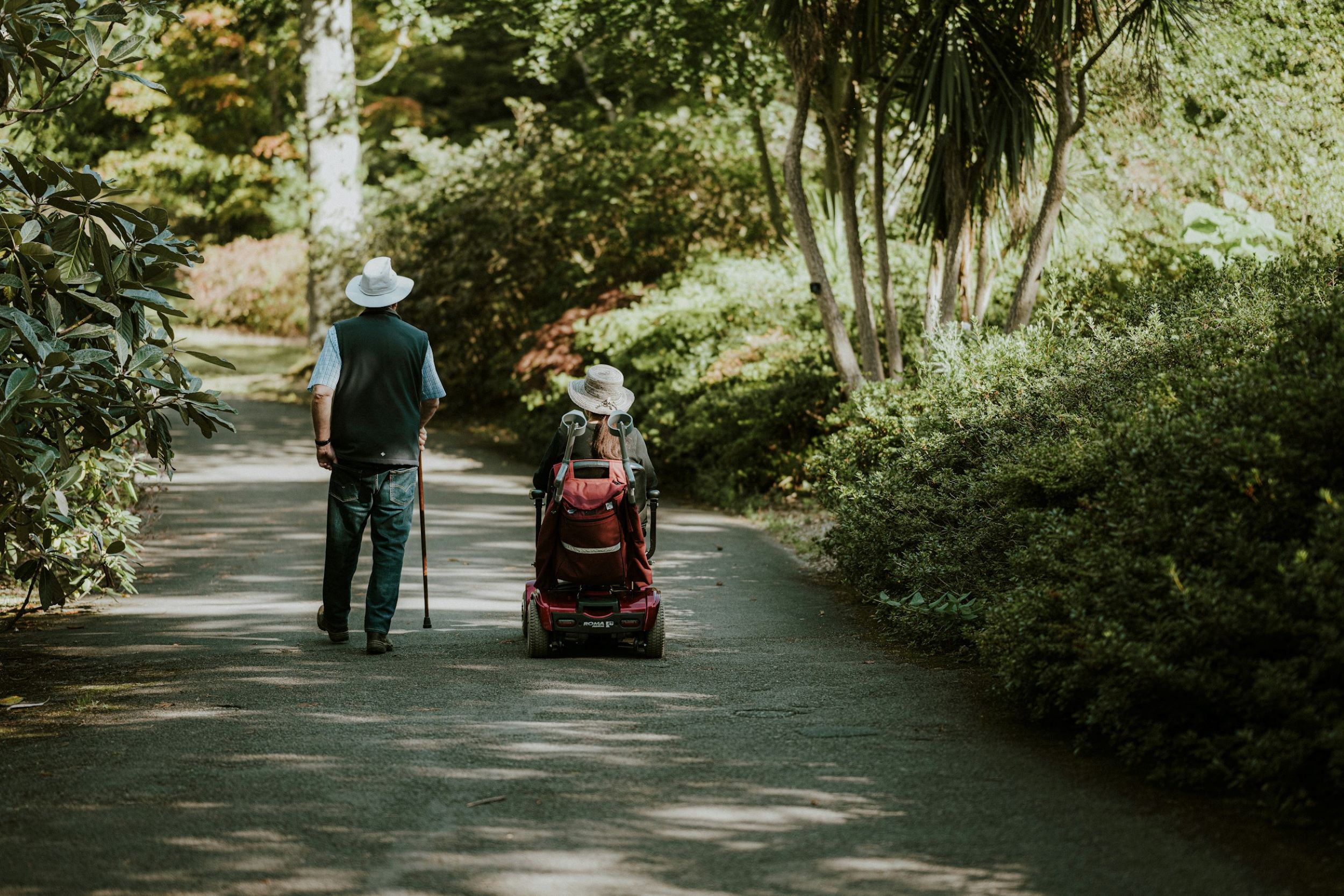 A man walks alongside a woman with a disability.