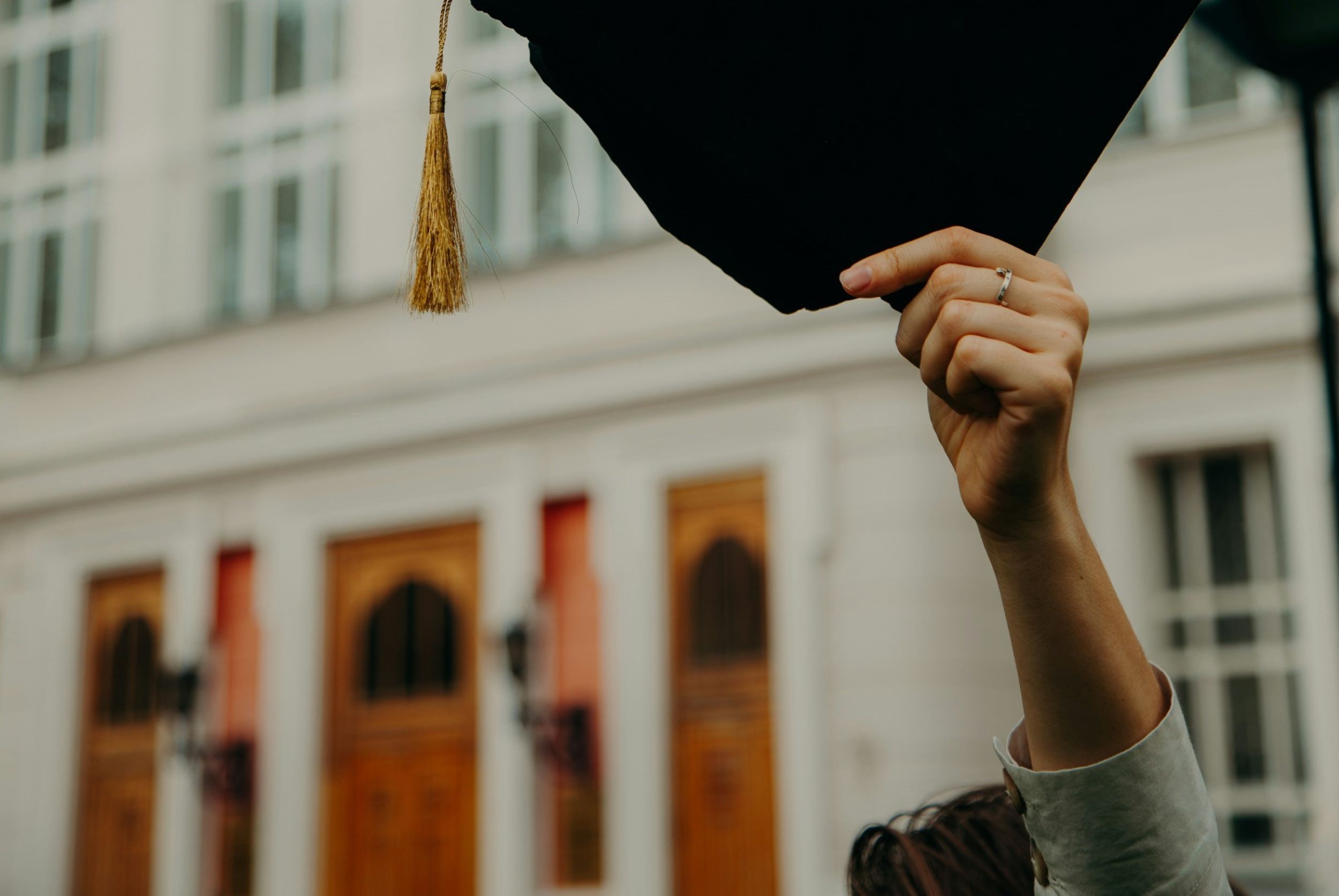 A student clutches his graduation hat.
