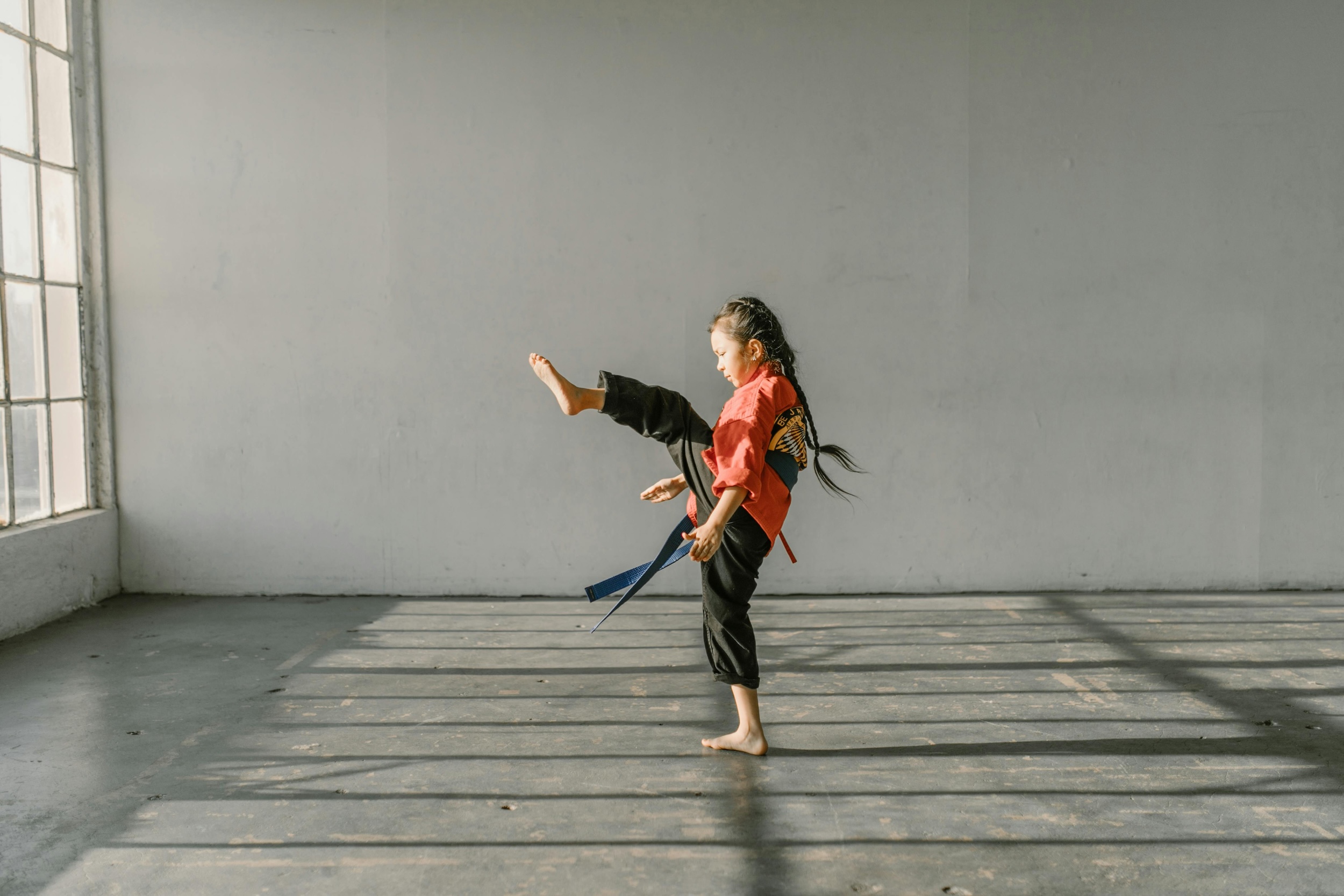 A young girl trains in a well-lit dojo.