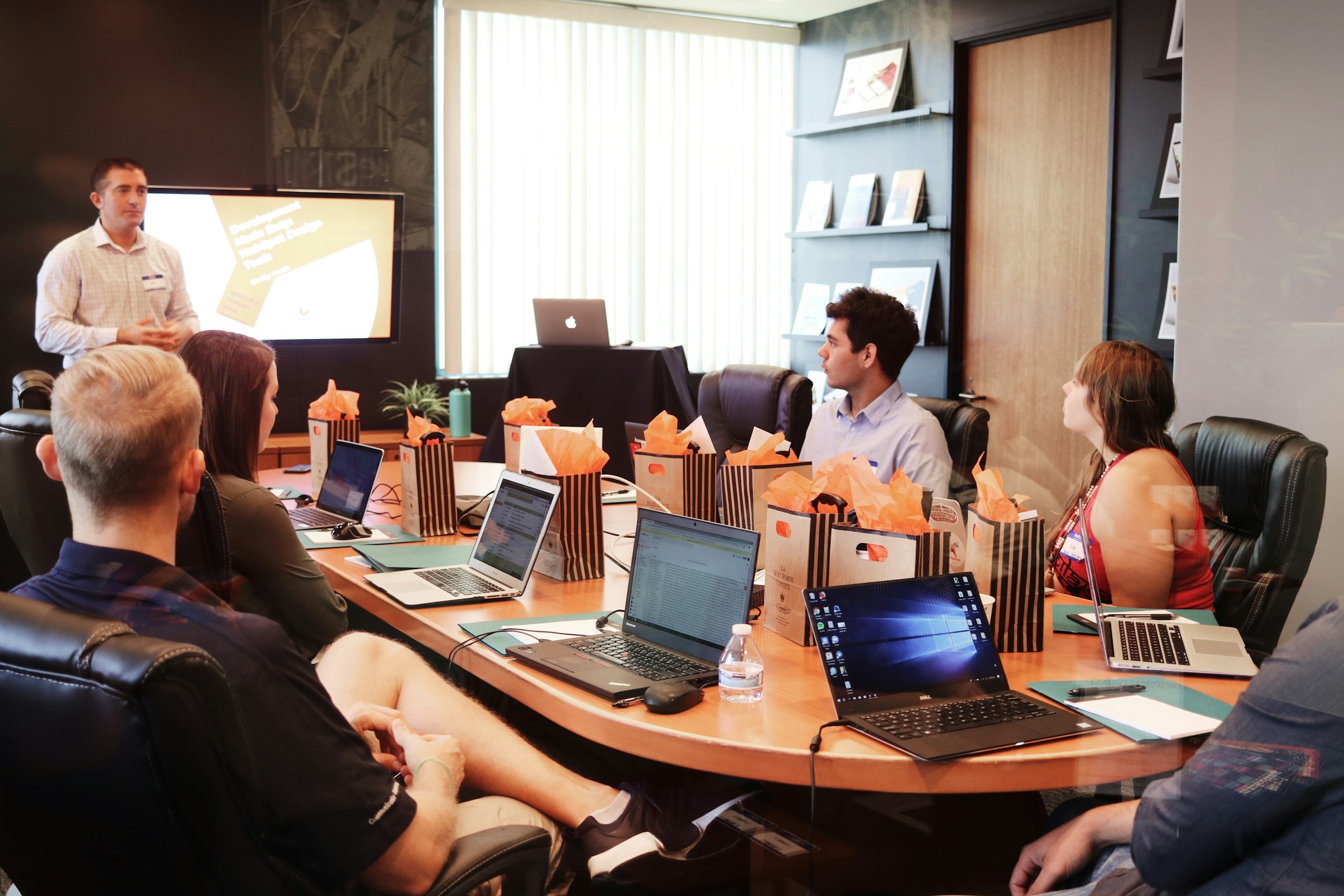 A group of people sit in a small office with laptops.