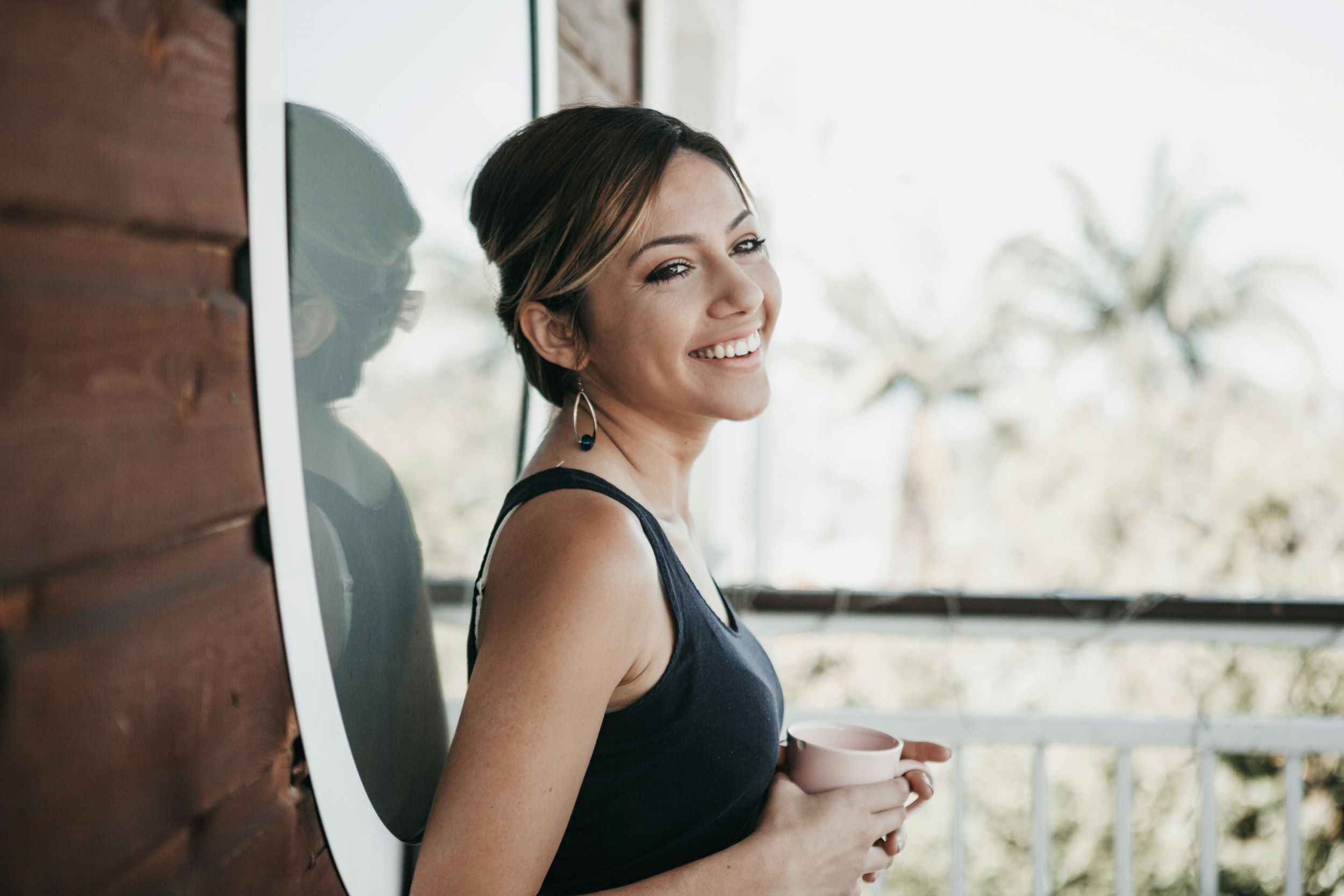 A woman smiles while clutching onto a coffee mug.