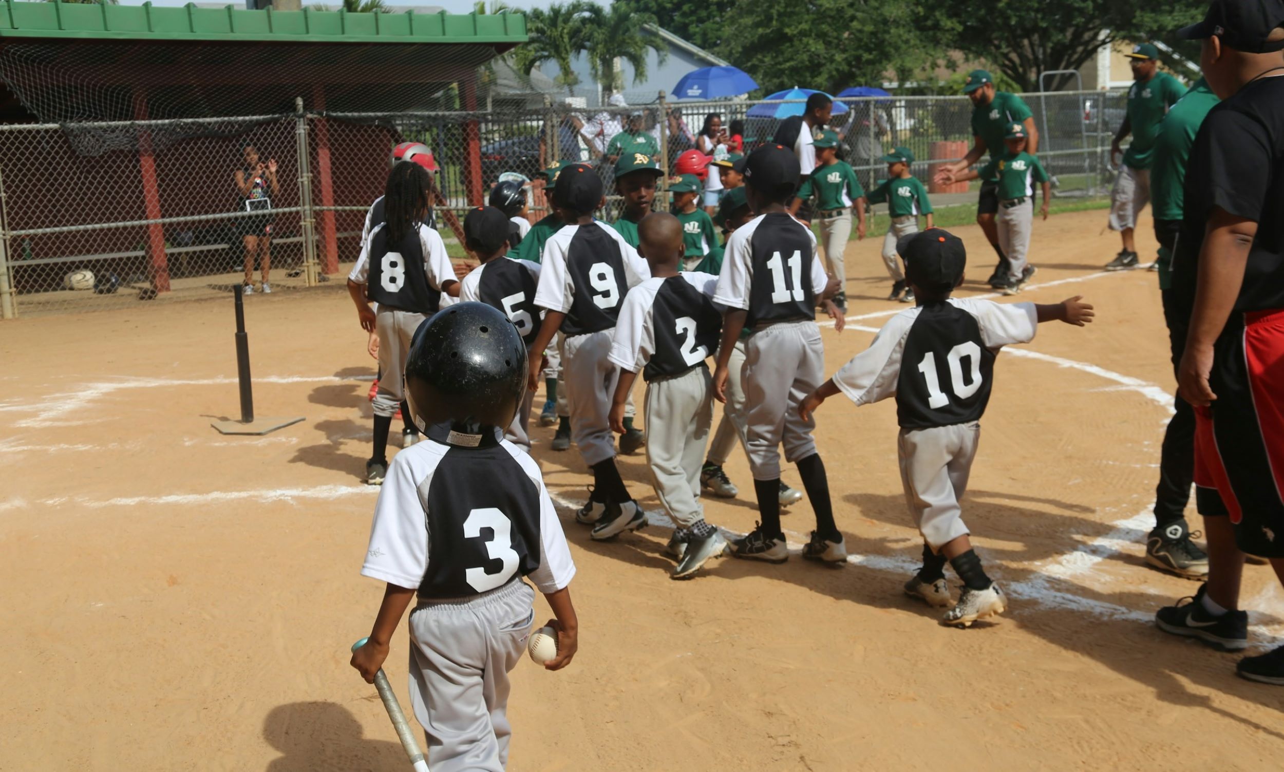 Young players, dressed in baseball uniforms, walk together to the dugout.