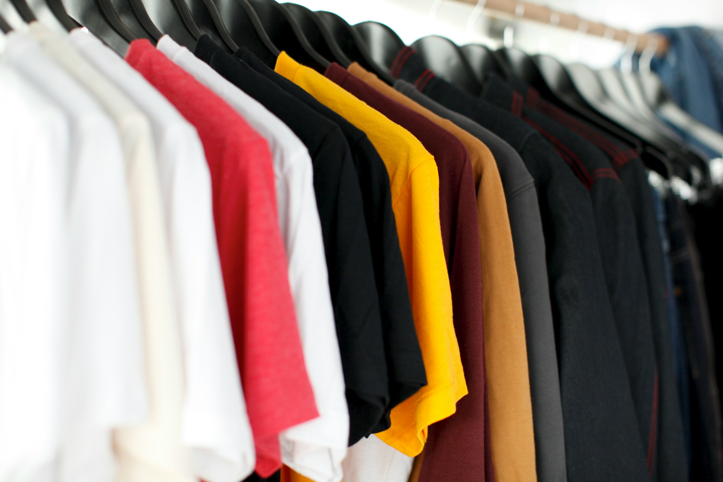 Shirts in a variety of colors and sizes hang neatly on a rack.