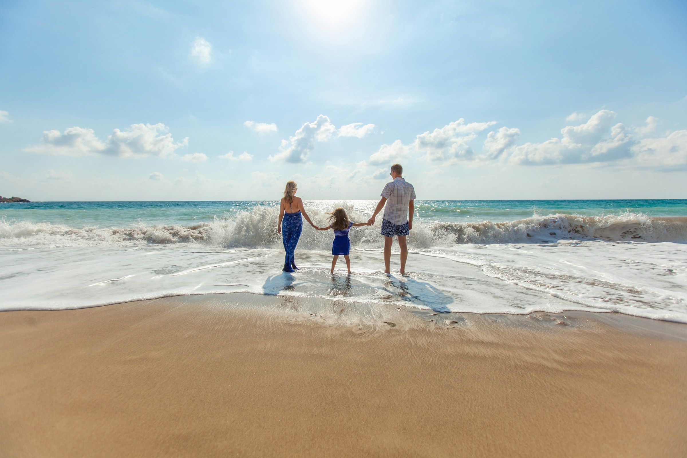 A family stands hand in hand on the beach, enjoying a sunny day together.