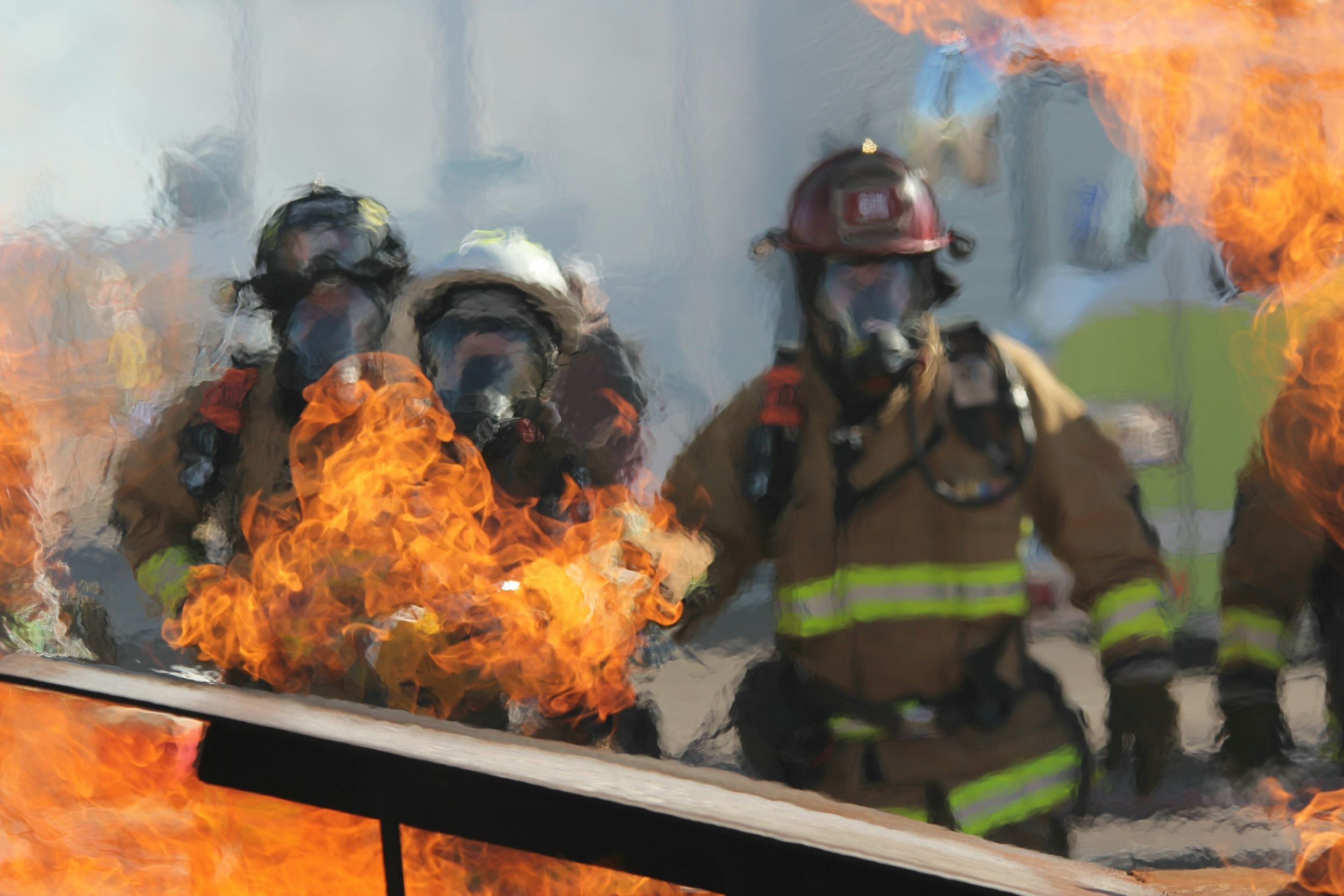 Four firefighters walk toward a burning object.