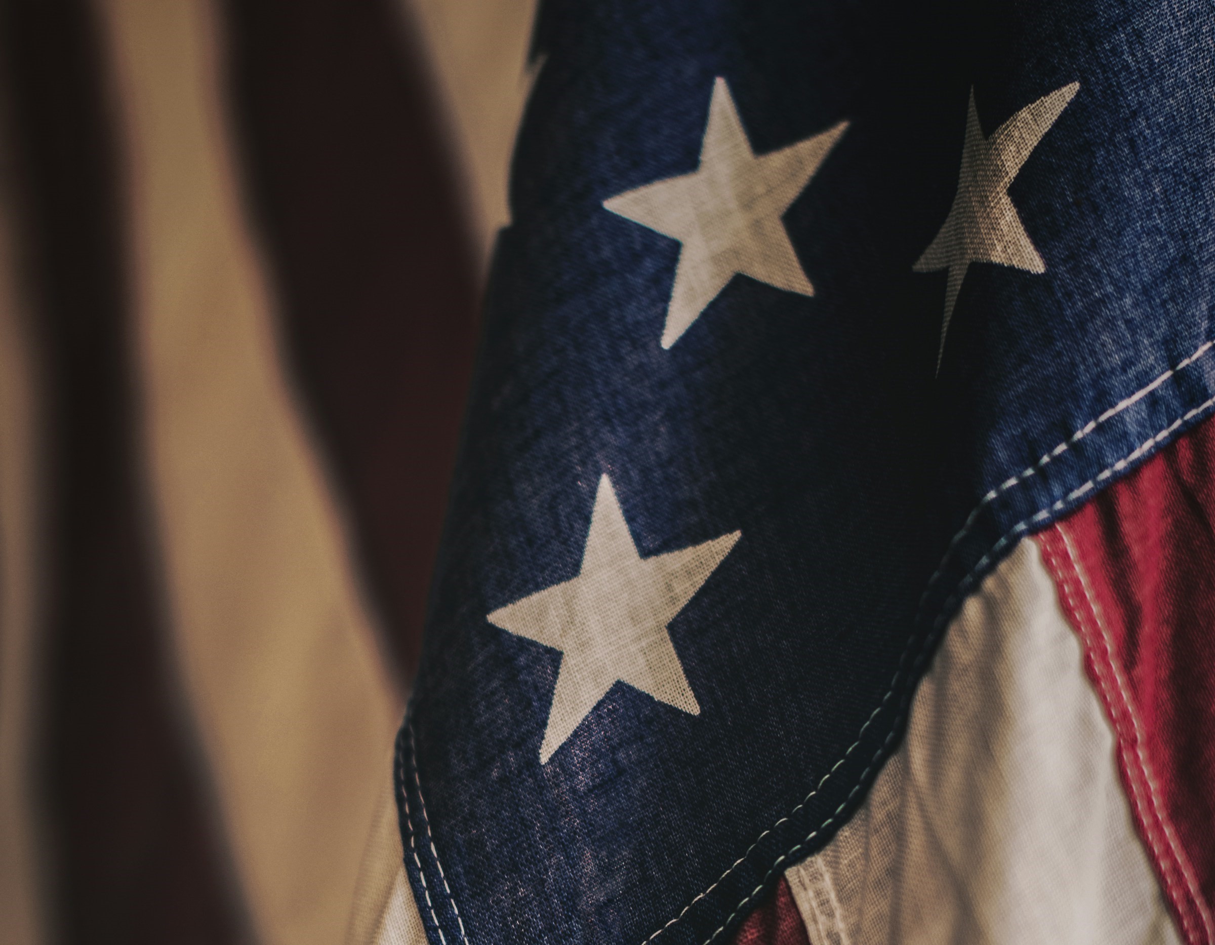 An American flag is positioned in front of a beige backdrop.