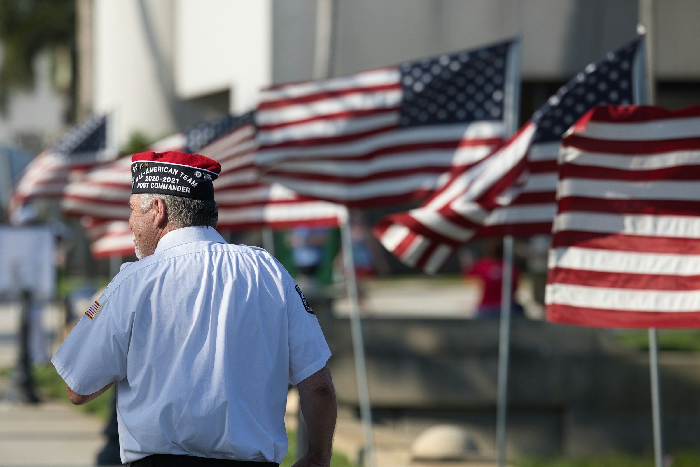 A veteran walks past to a row of American flags.
