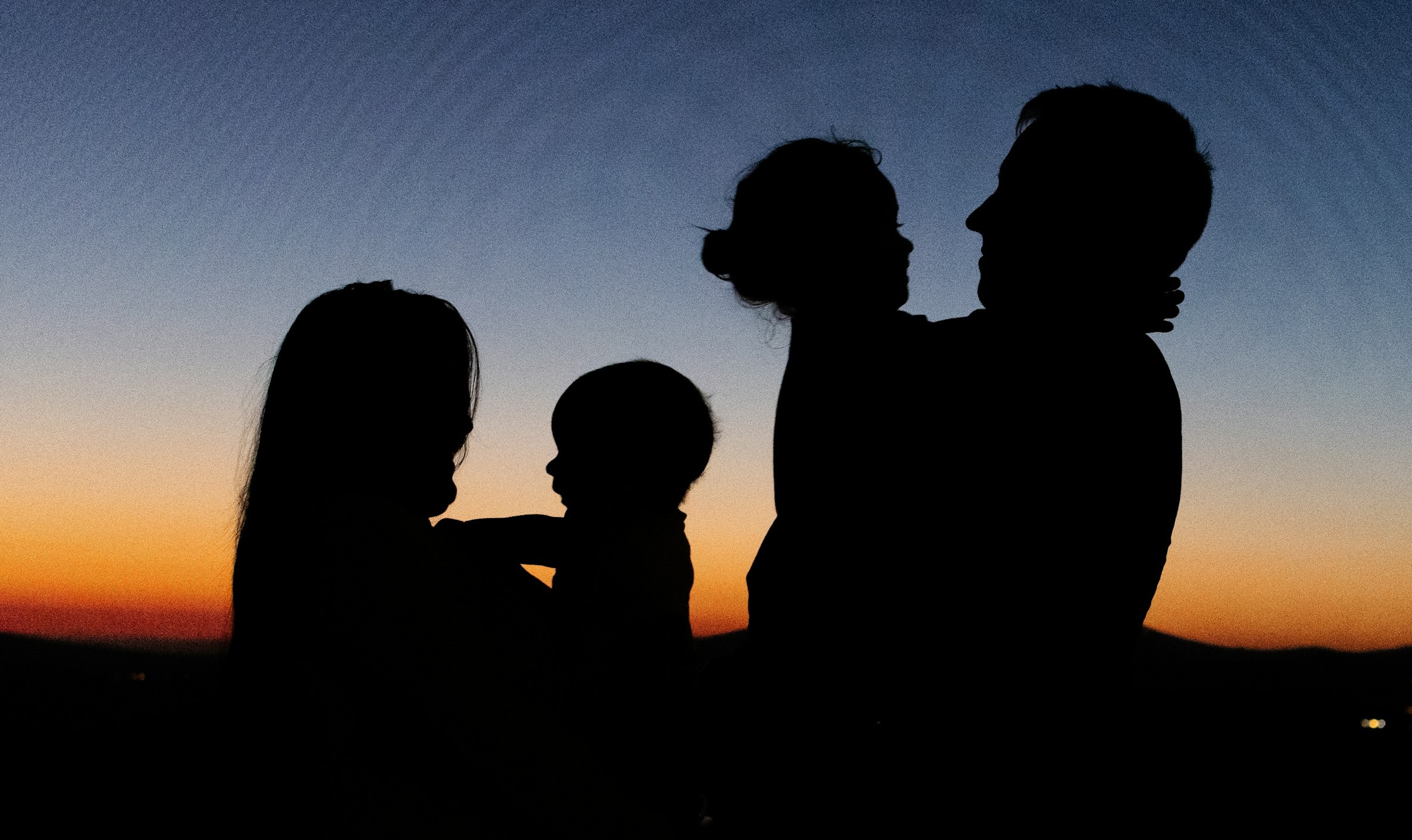 A family embraces during sunset.