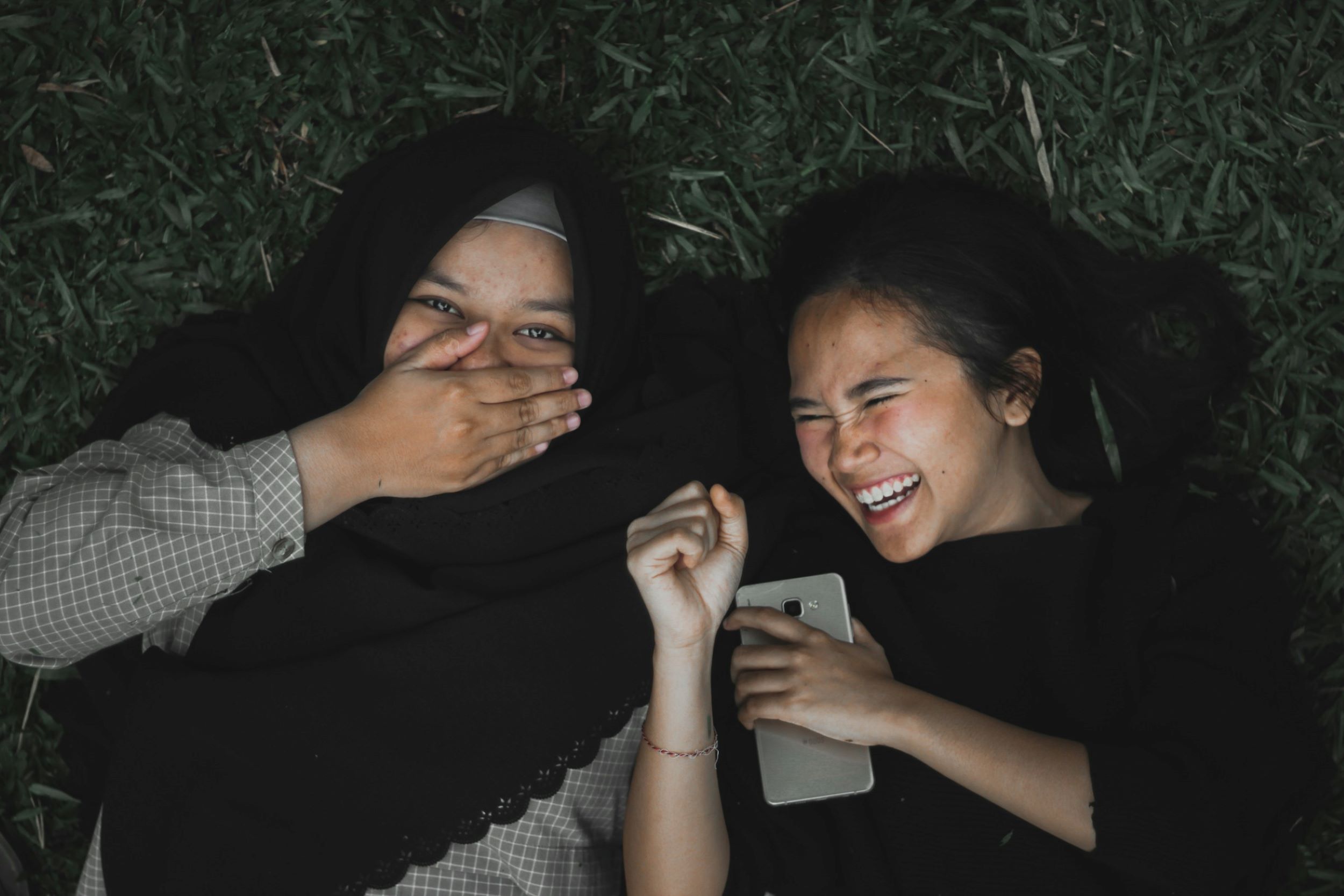 Lying on the ground, the two girls laugh joyfully.