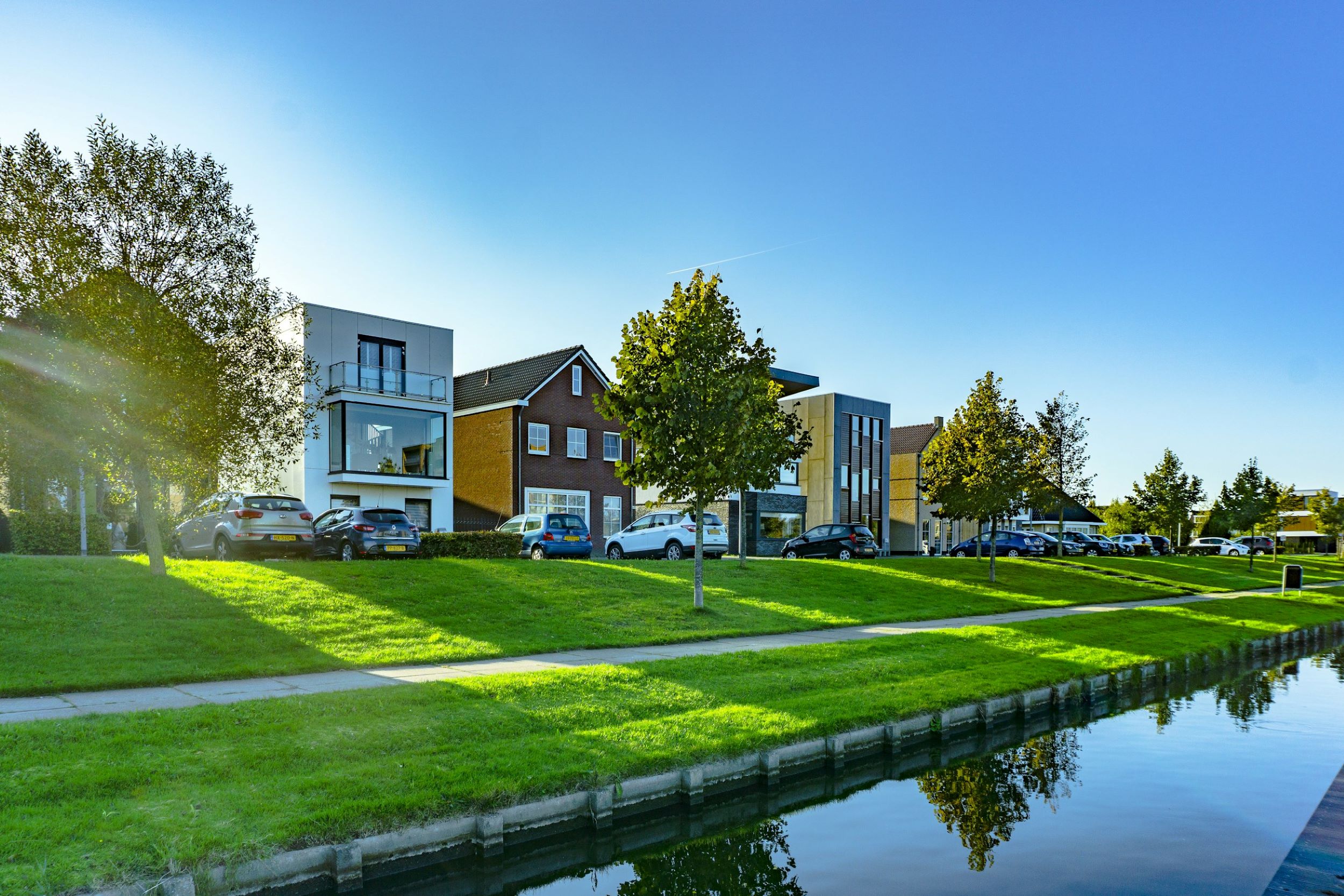 A row of modern houses are positioned in front of a small lake.