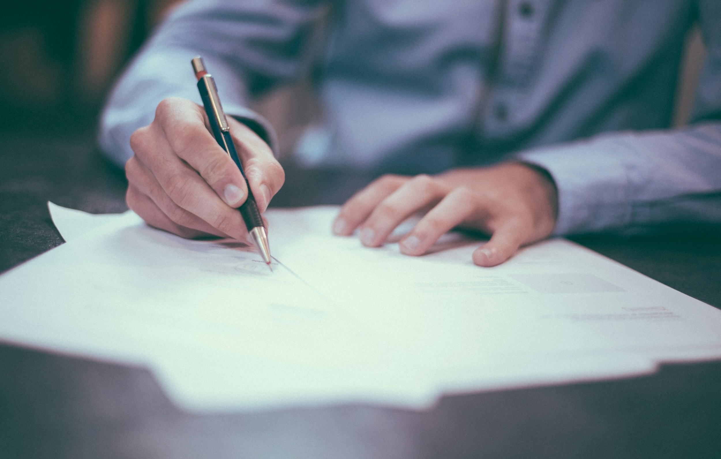 A lawyer sits at a desk and scribbles on paper.