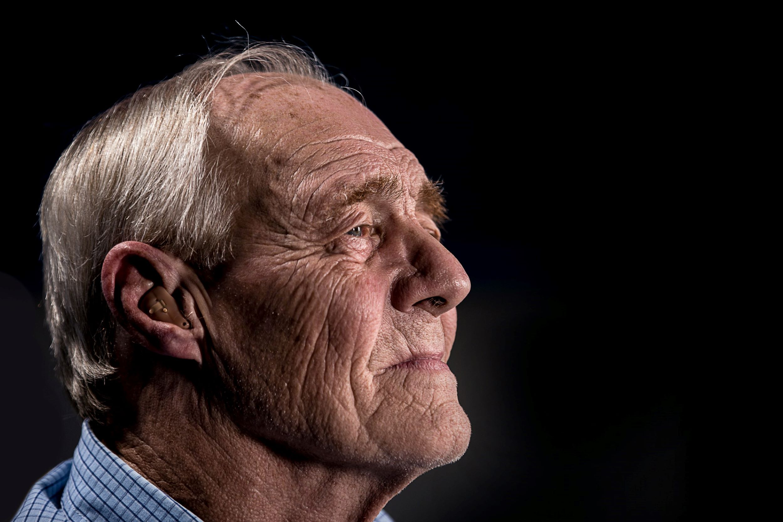 A side profile of a senior deep in thought, set against a dark, minimalist background.