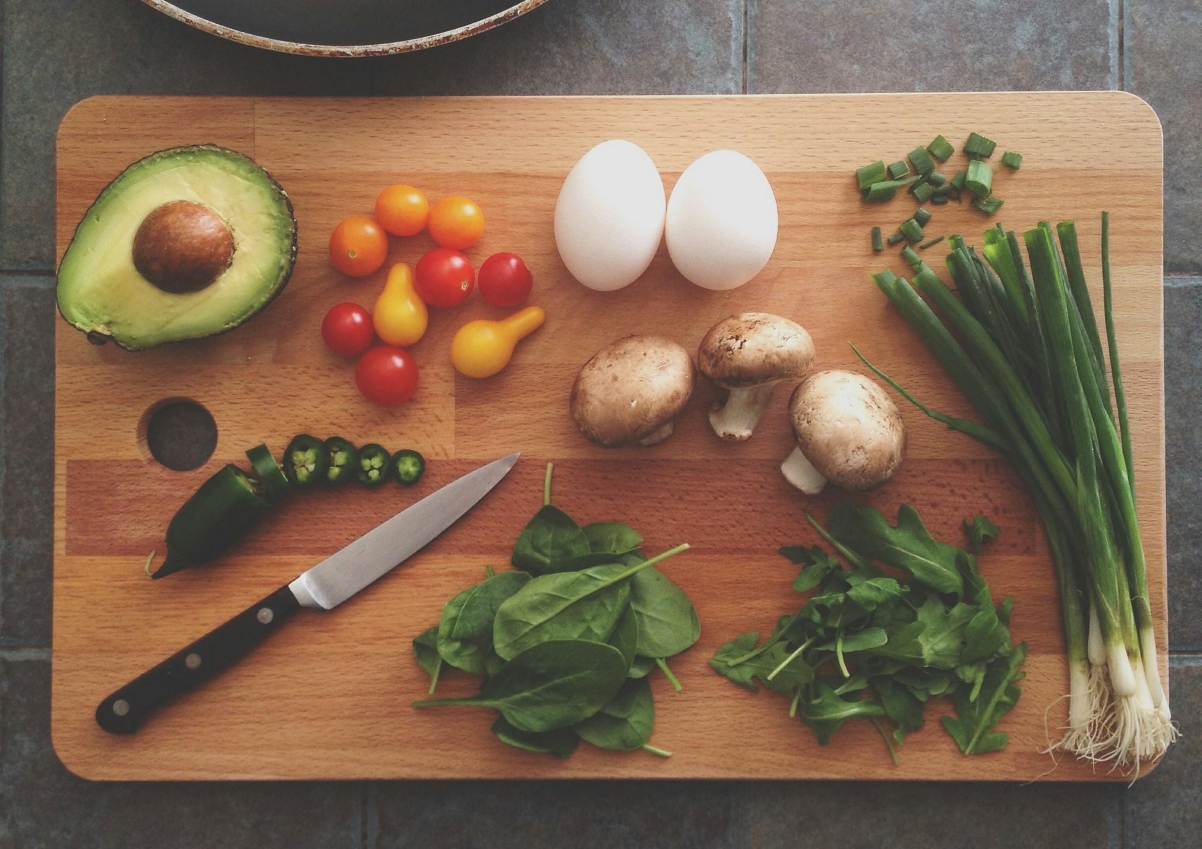 Vegetables and herbs are positioned on a chopping block.