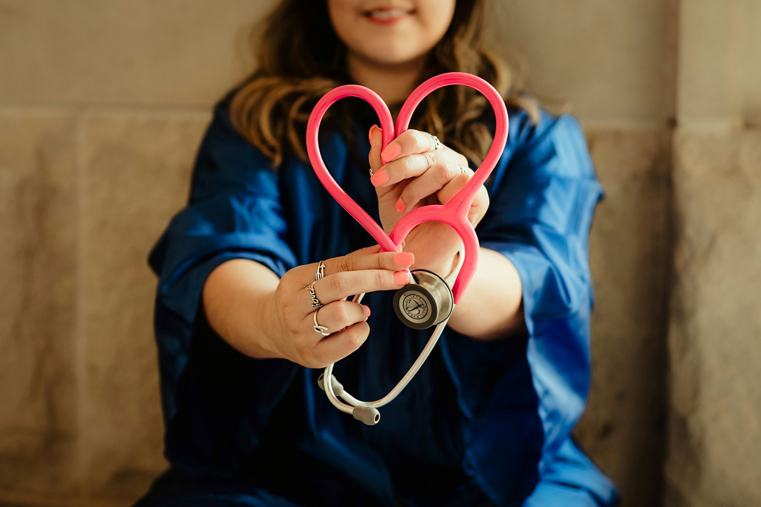A doctor shapes her stethoscope in the shape of a heart.