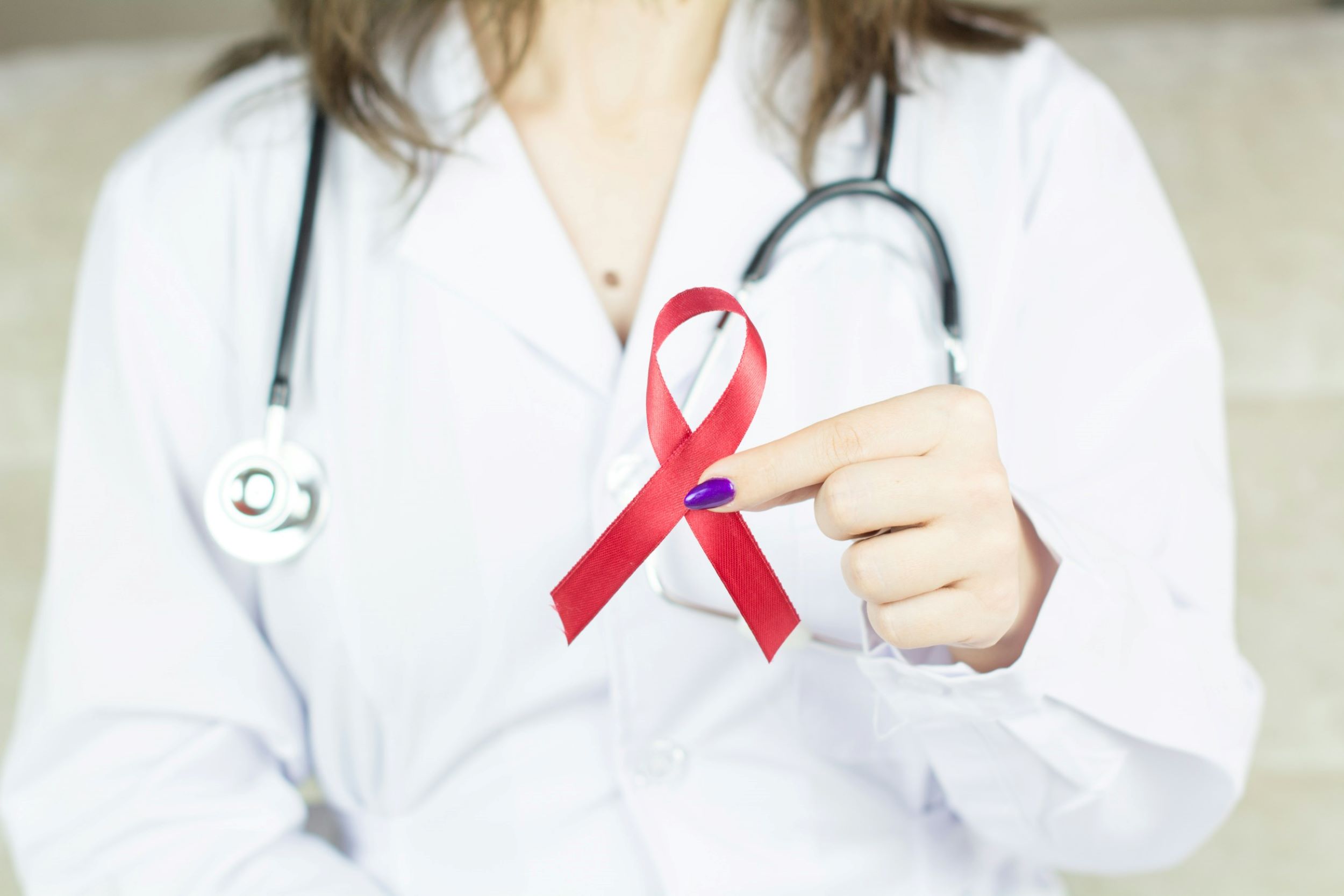 A doctor clutches a red ribbon between her fingers.