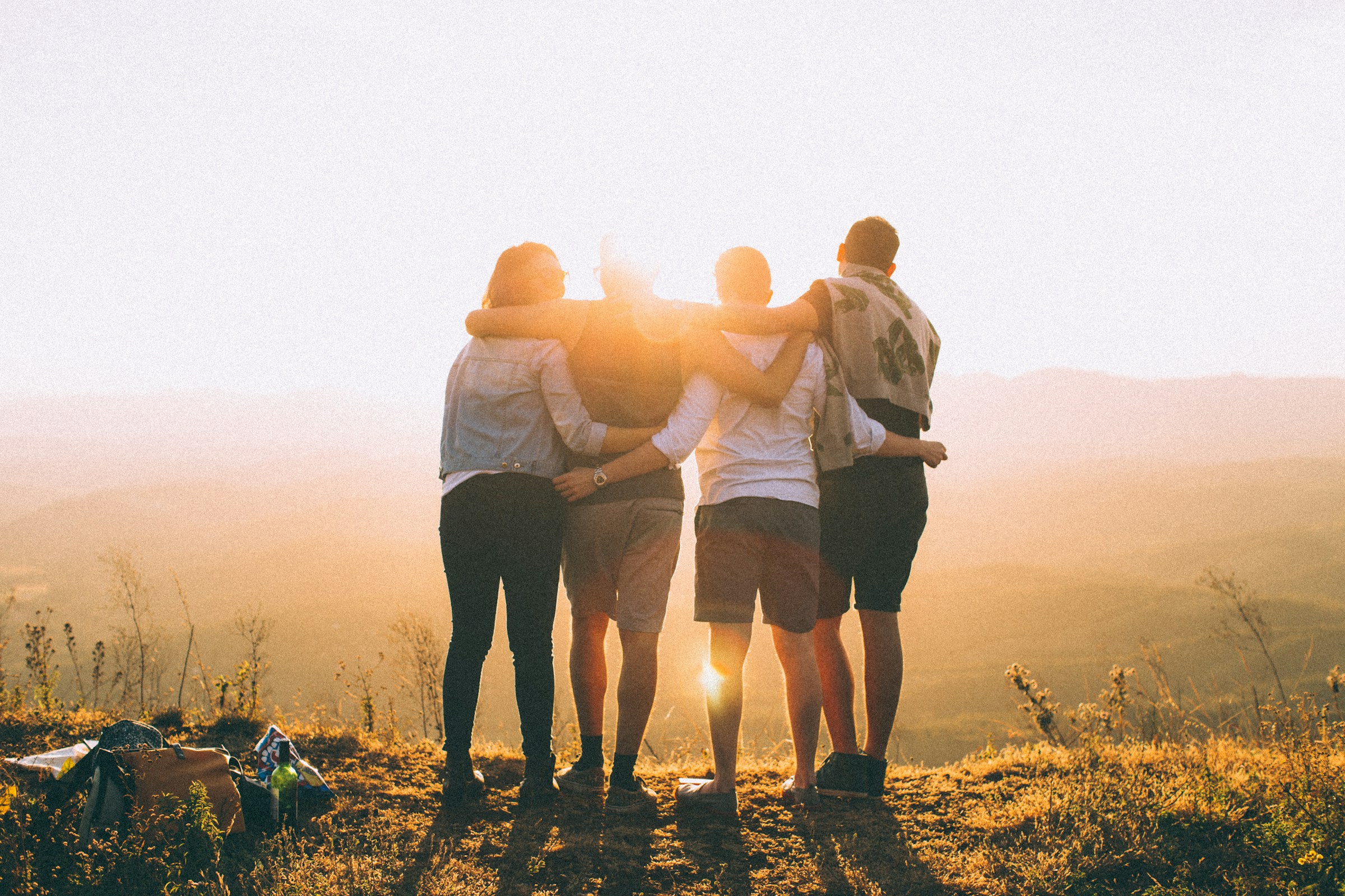 Two men and two women stand on a high mountain and embrace.