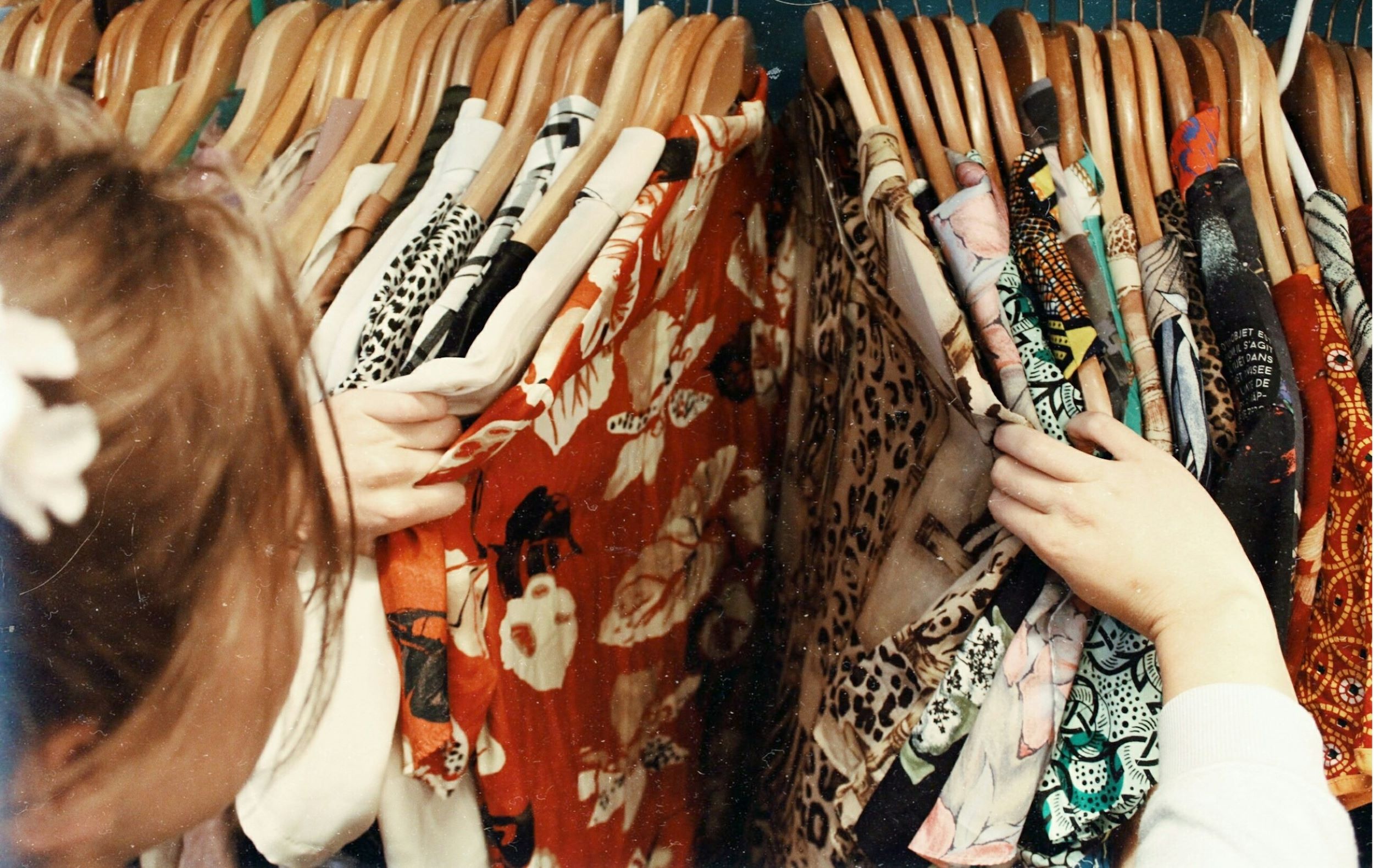 A woman runs her hands through a selection of clothing on a rack.