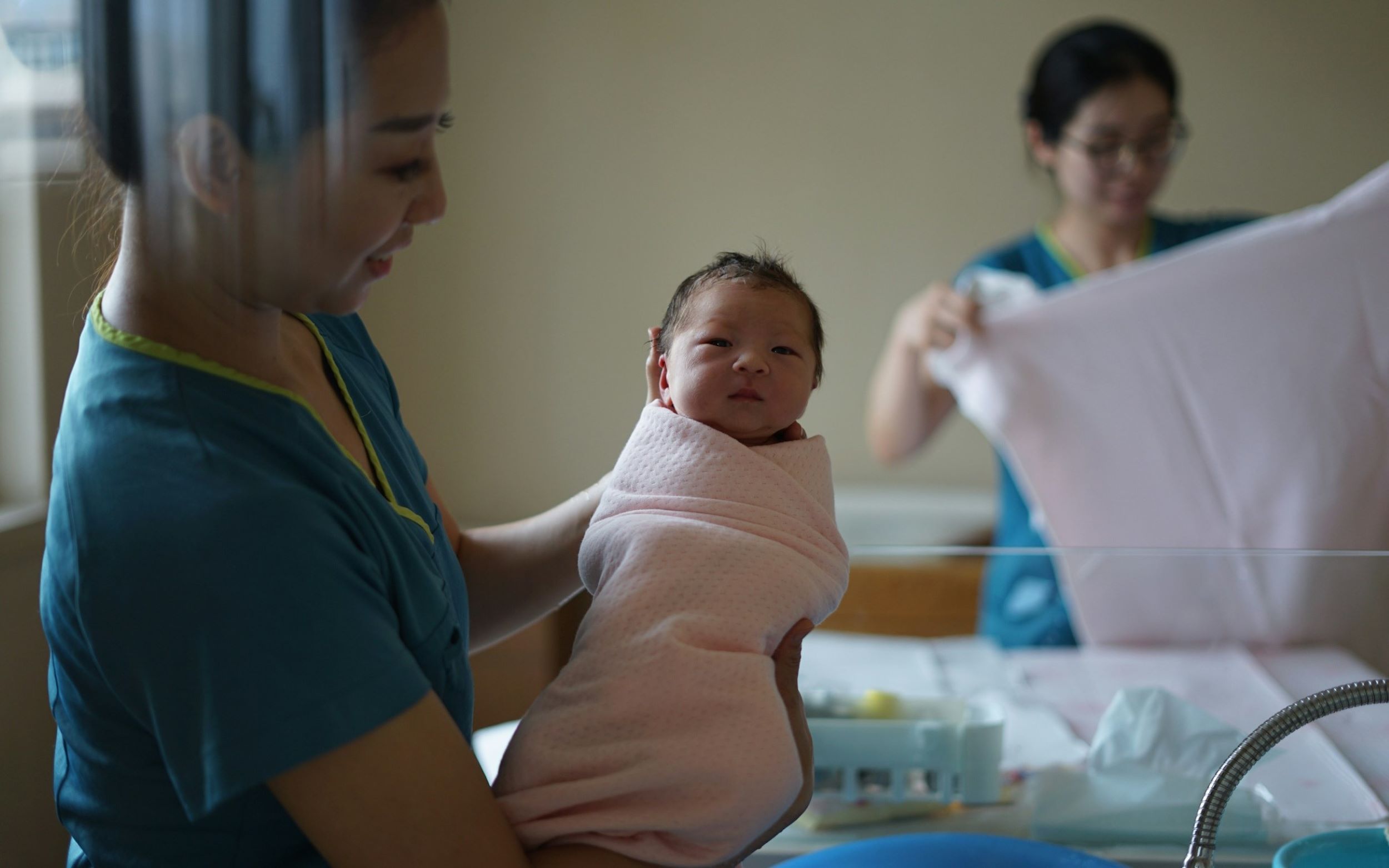A midwife smiles while holding a newborn.