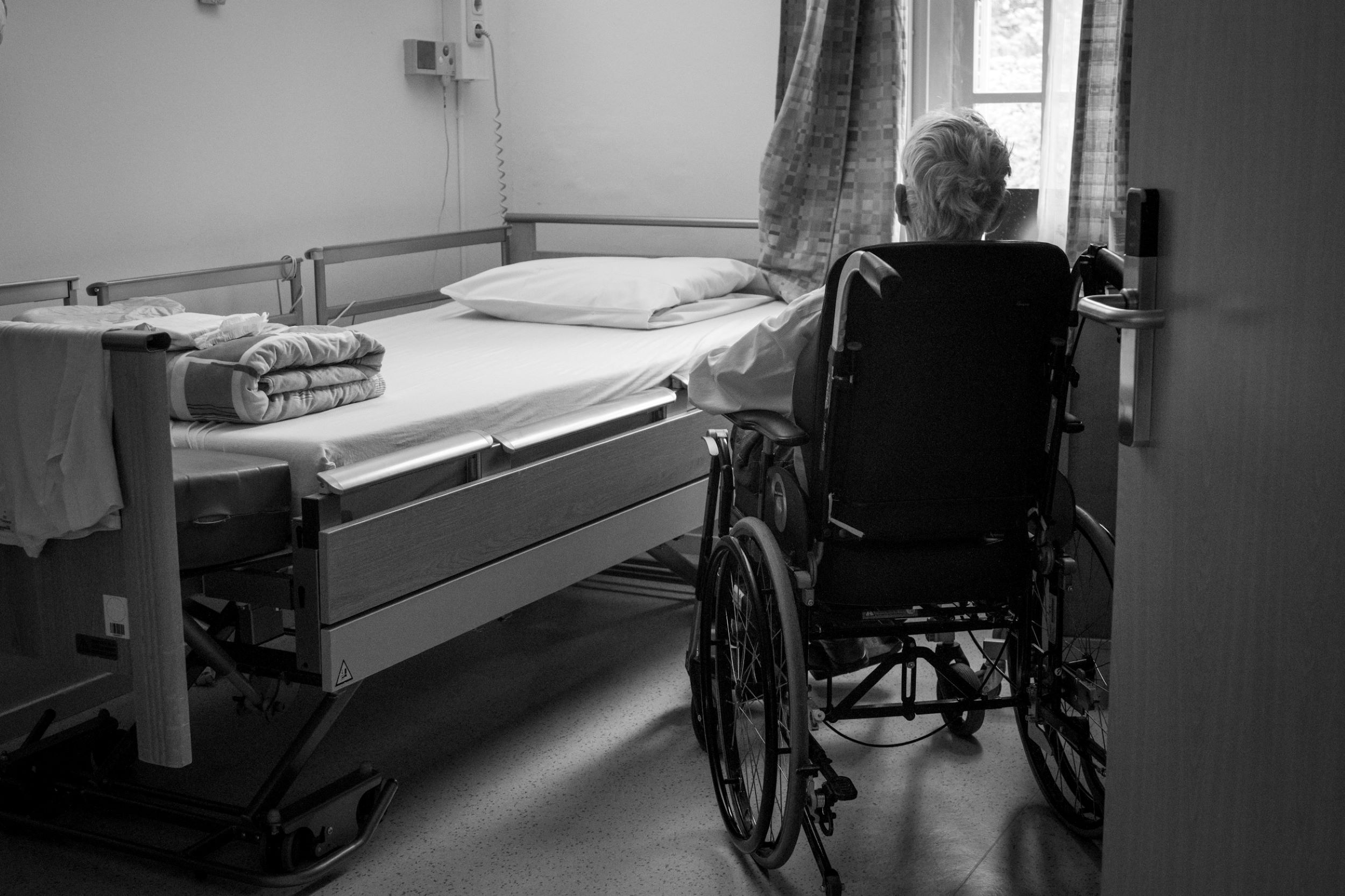 An elderly patient sits quietly in a wheelchair.