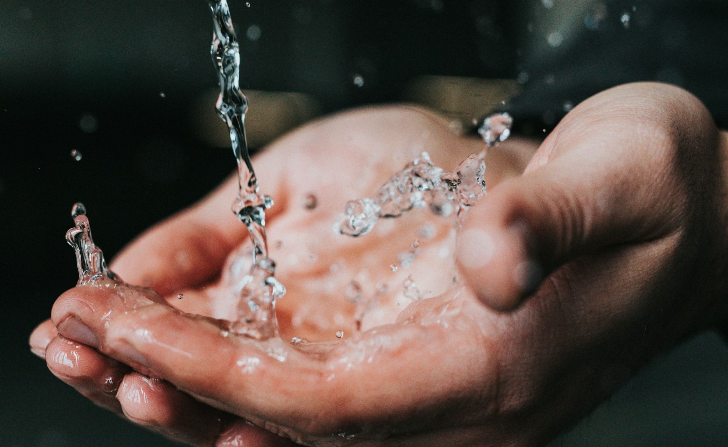  A man places his hands under a faucet with running water.