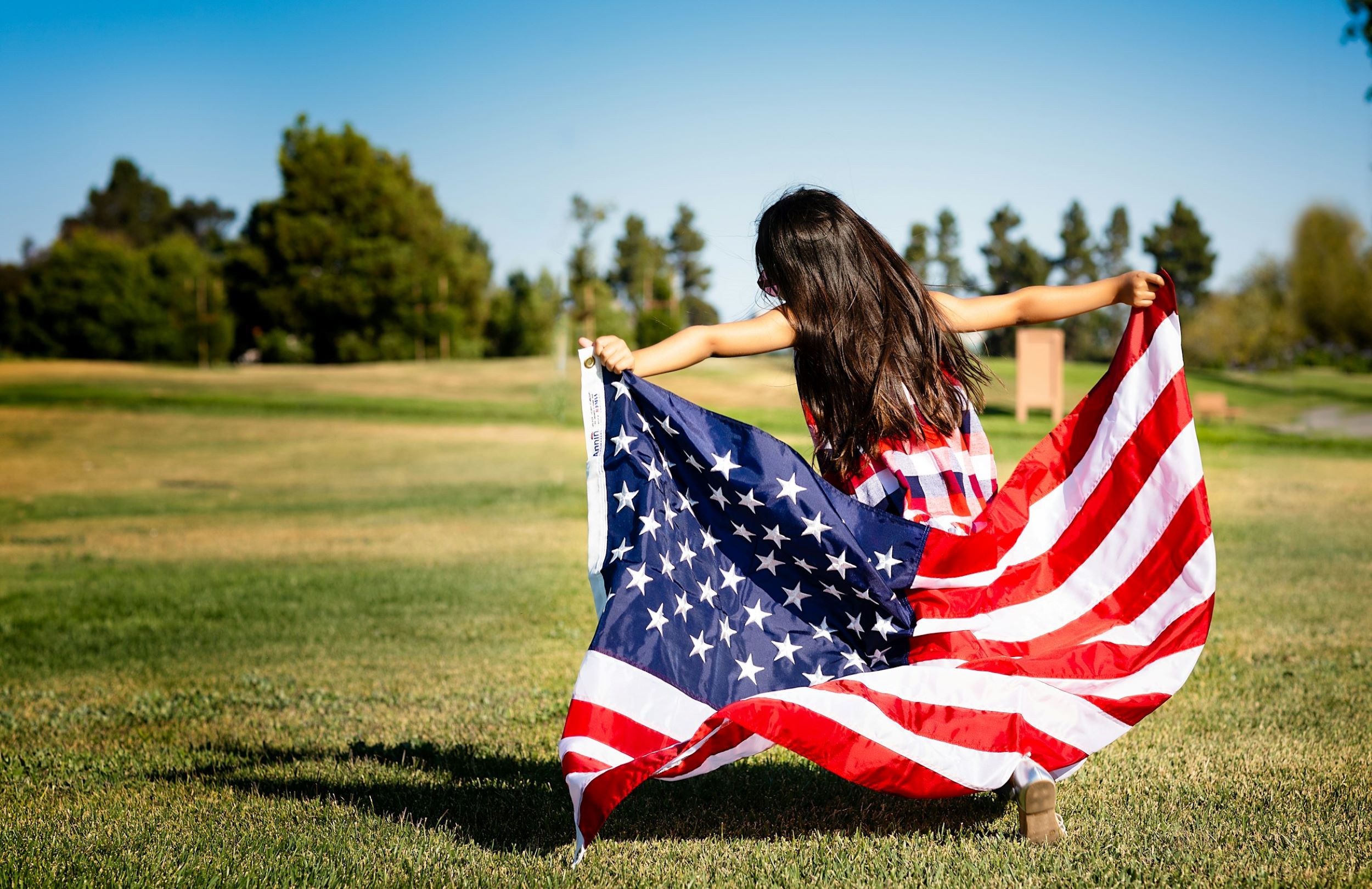 A young girl runs while clutching the American flag.