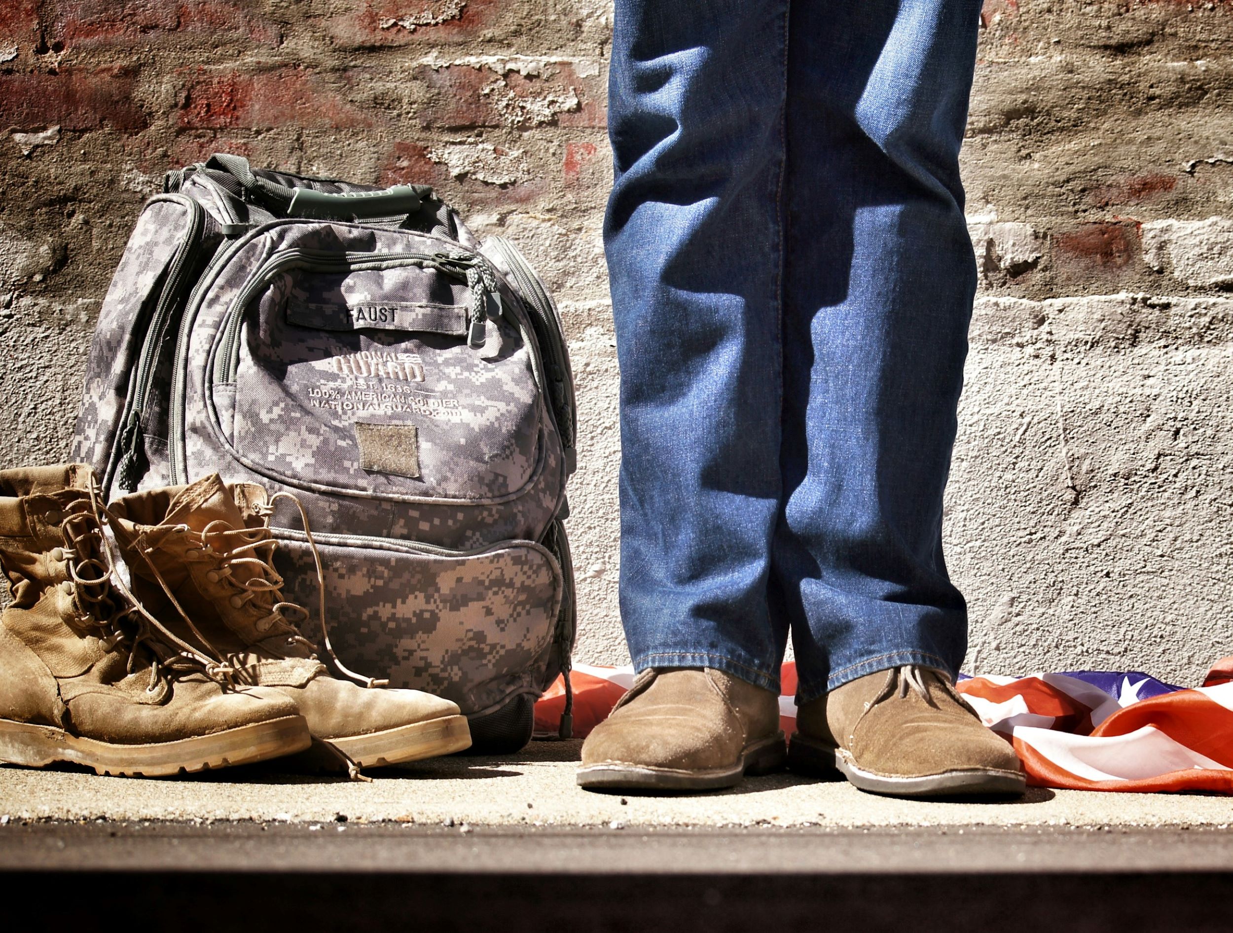An aging veteran stands next to his combat boots.